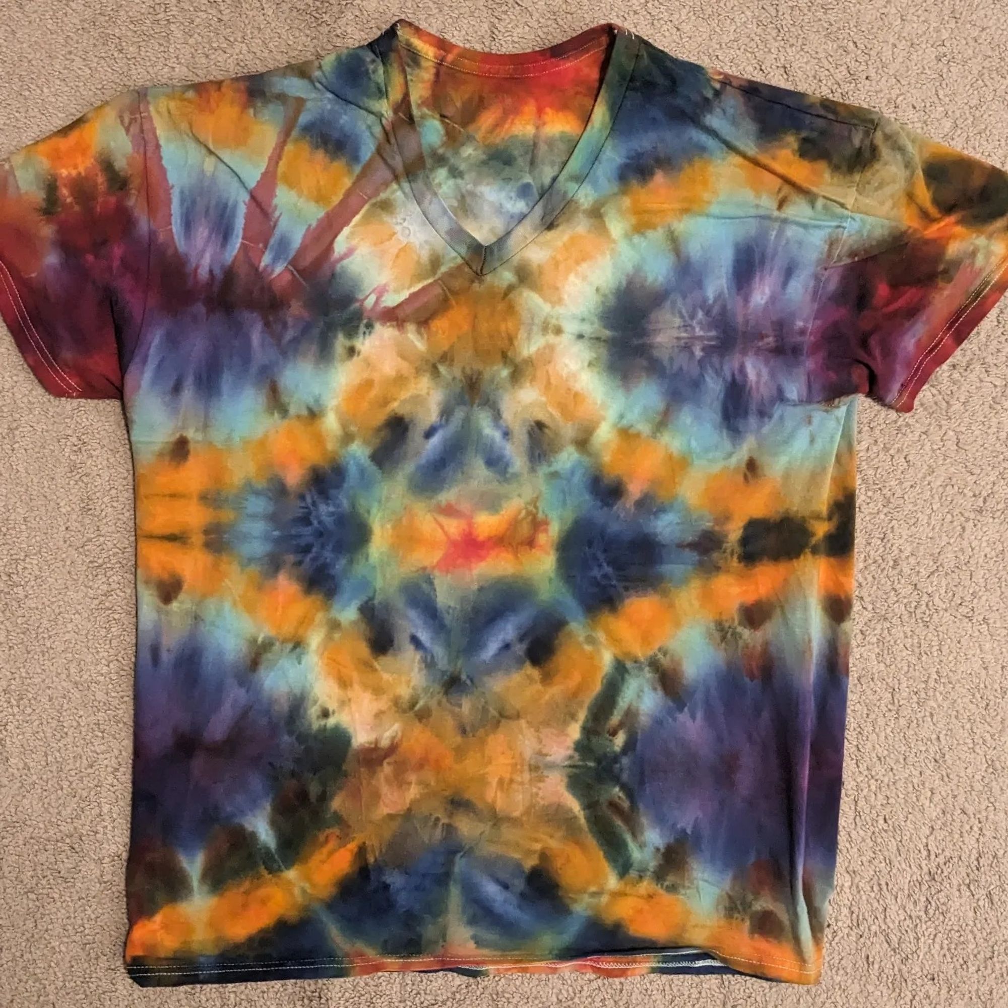 A double X pattern tie dyed shirt. It has orange, purple, reds, and blues.