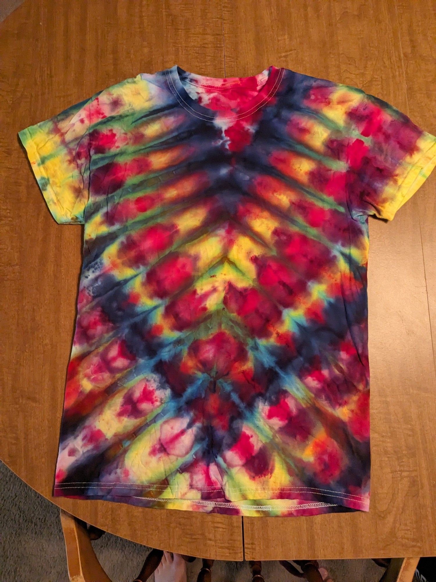 A deep V pattern tie dye shirt with yellow, blue, pink and green.