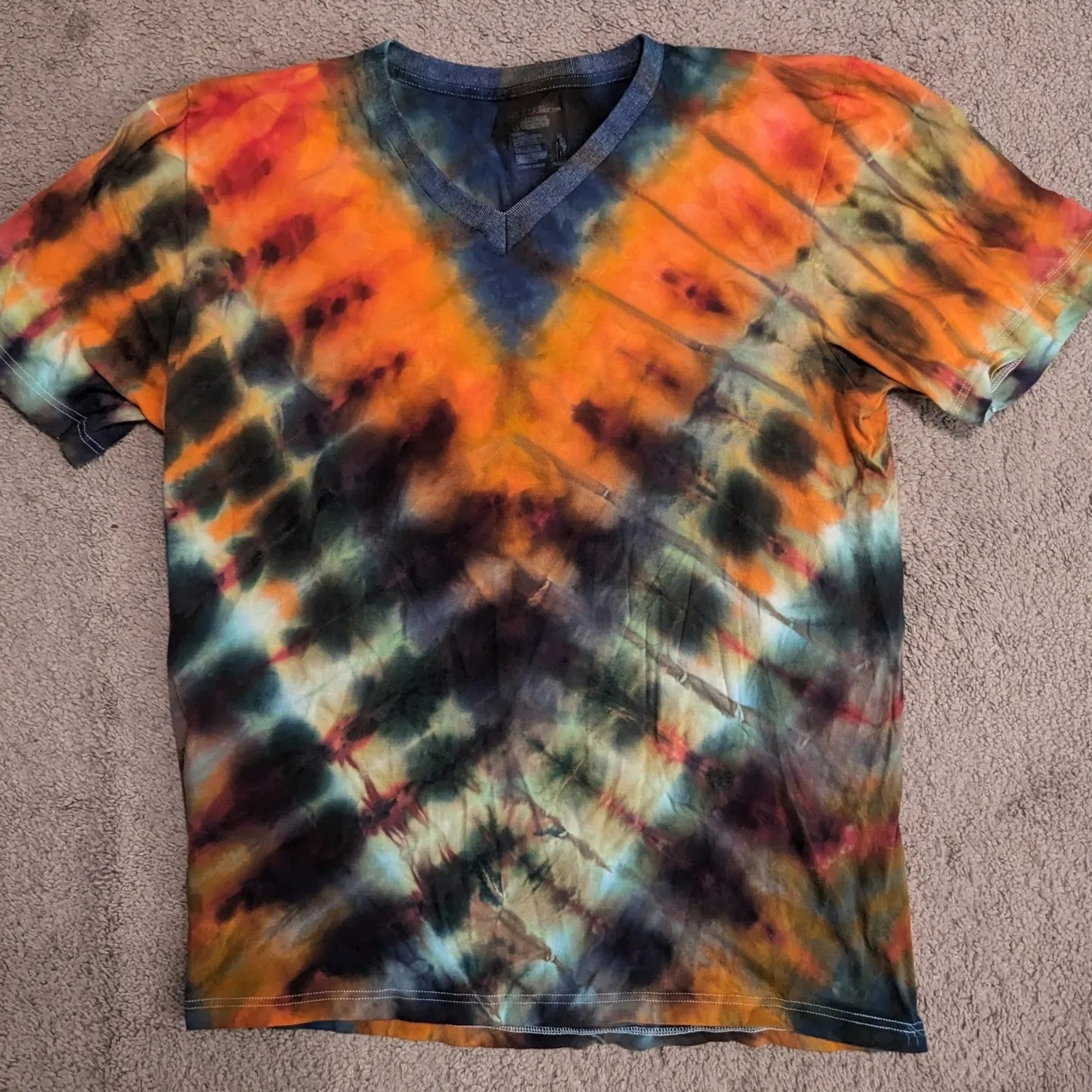 A deep V pattern tie dye shirt with orange, dark purple, and blue.