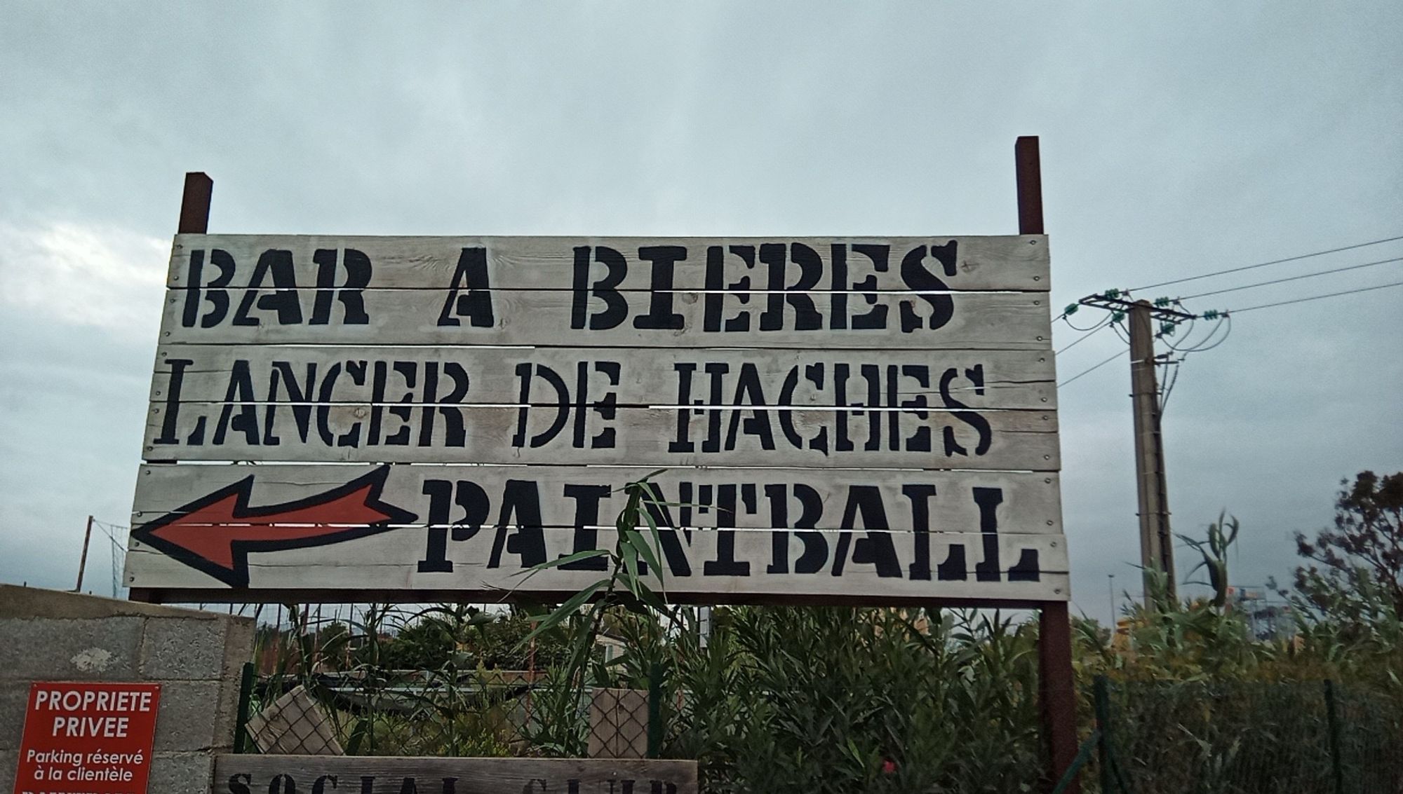 Schild "Bar a bières / lancer de haches / paintball".