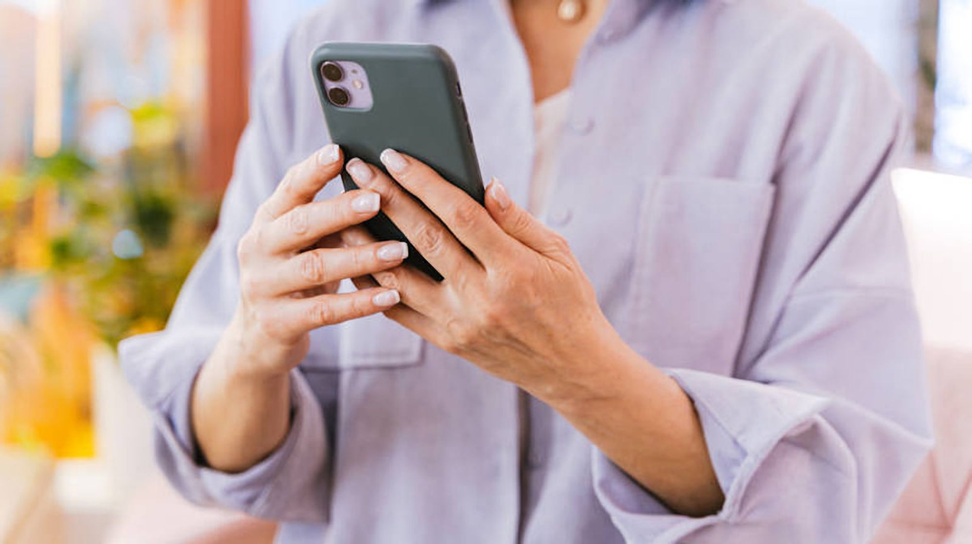 Bildbeschreibung: Eine Frau die ein Smartphone in der Hand hält.