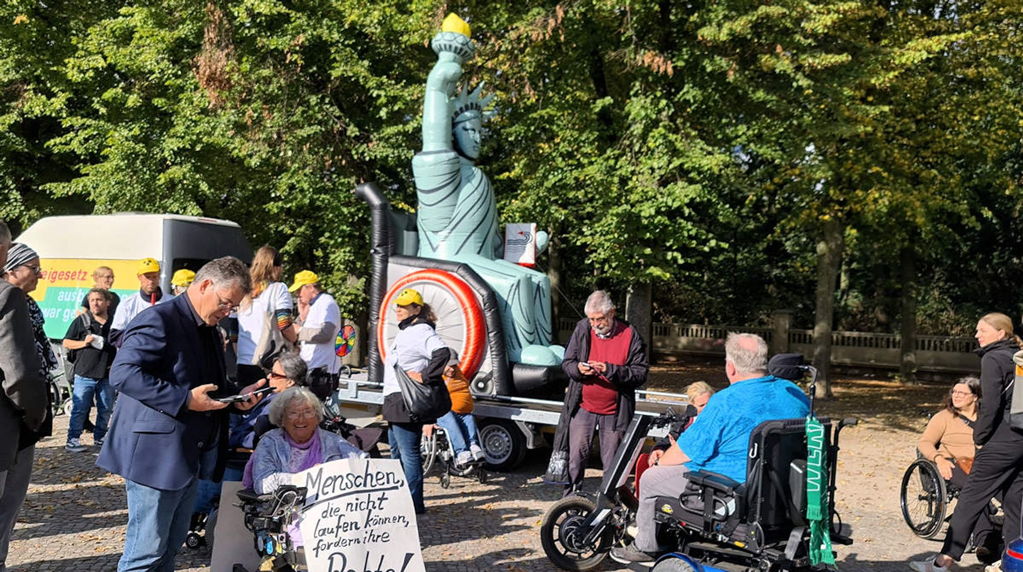 Bildbeschreibung: Demo zur Barrierefreiheit am Brandenburger Tor mit der Freiheitsstatur im Rollstuhl.