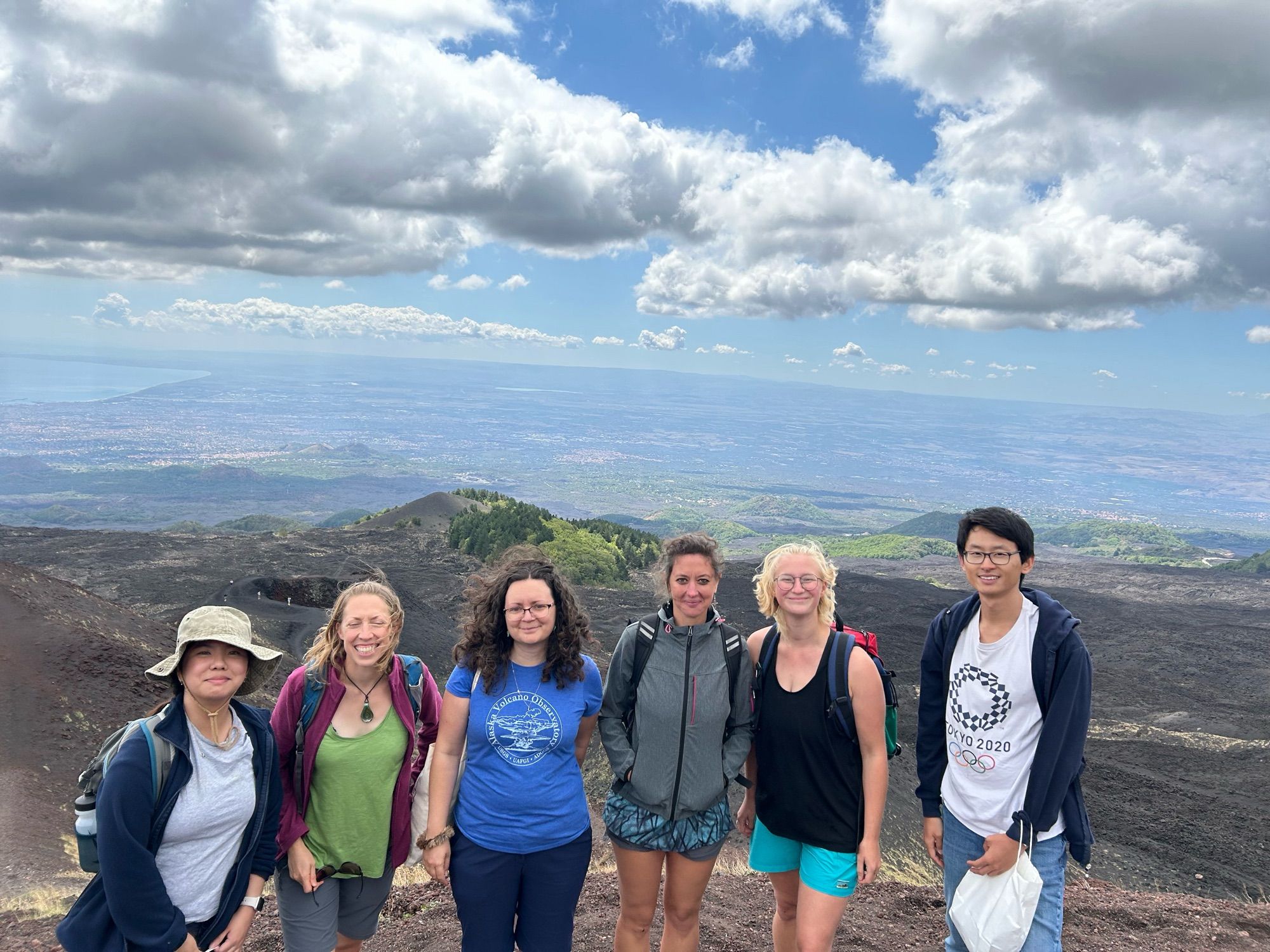 The same 6 people, this time with a view below into the cones and lava flows on the  volcanoes slopes. You can just make out the sea in a bay in the distance.