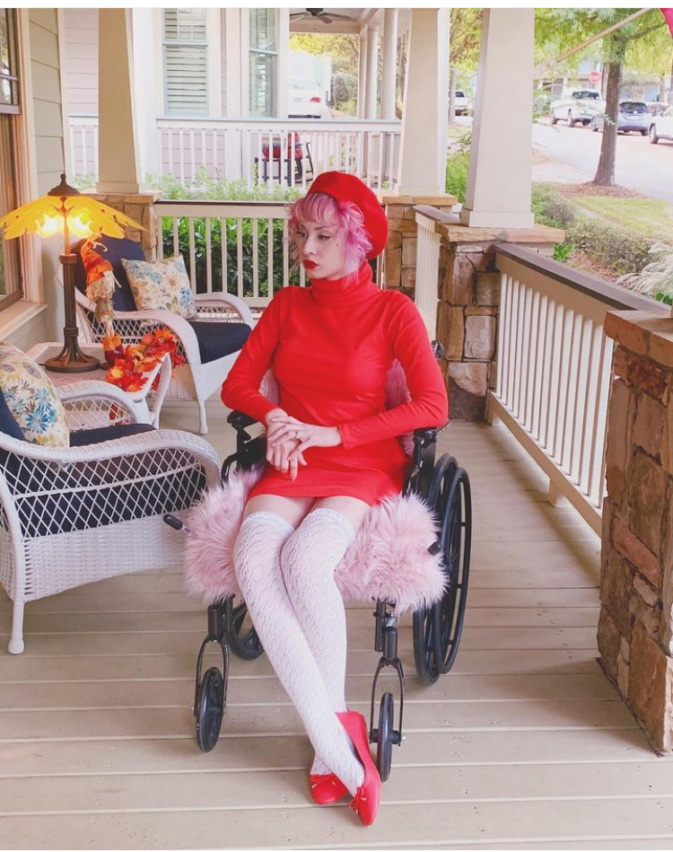 picture of me 4 years ago on a porch sitting in a black and pink wheelchair wearing all red looking like i mentally gave up