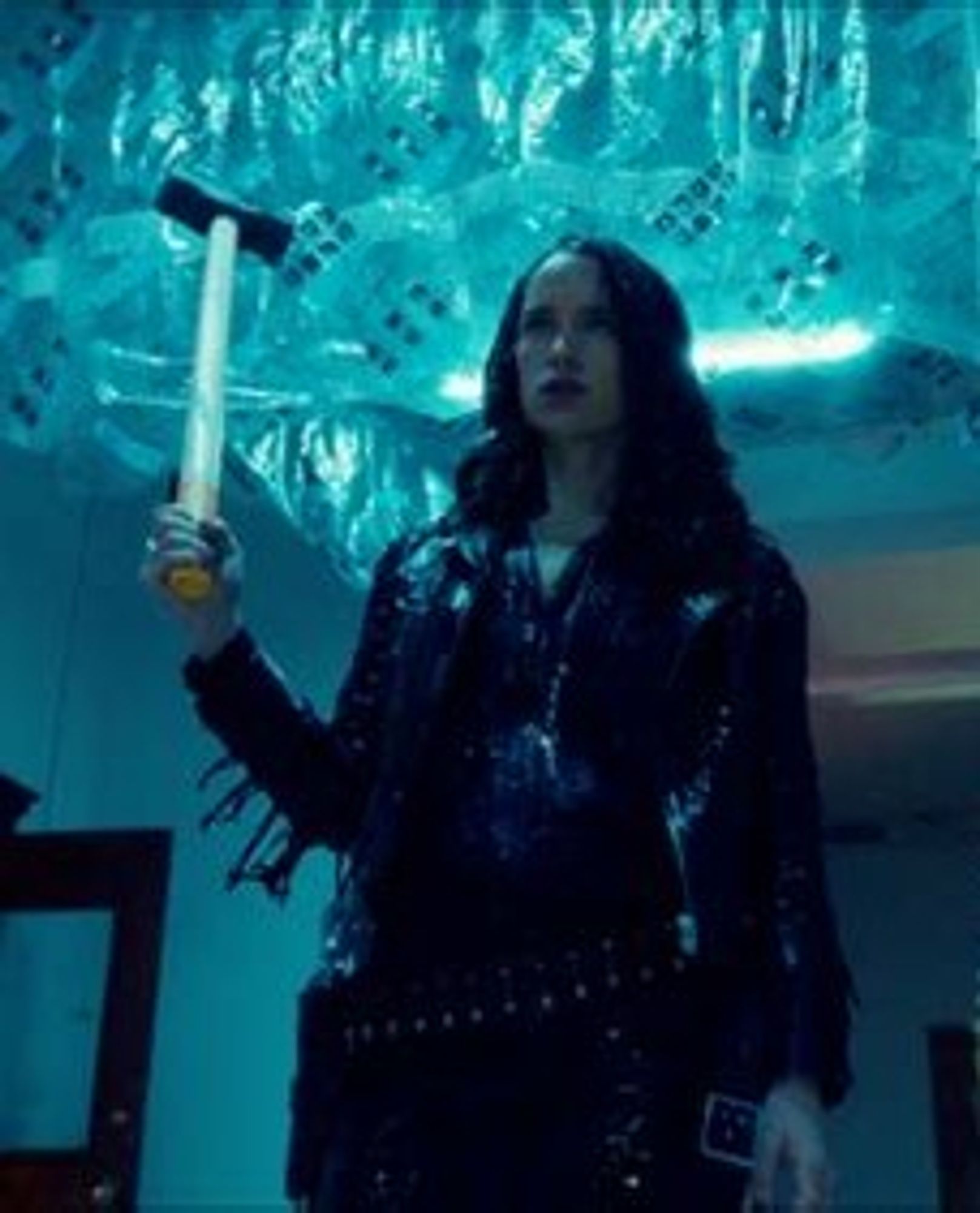 An image of Melanie Scrofano as Wynonna Earp.  She is lit with a blue light, and covered in slimy ooze. She is carrying a sledge hammer (I think) in one hand.  She does not look happy.