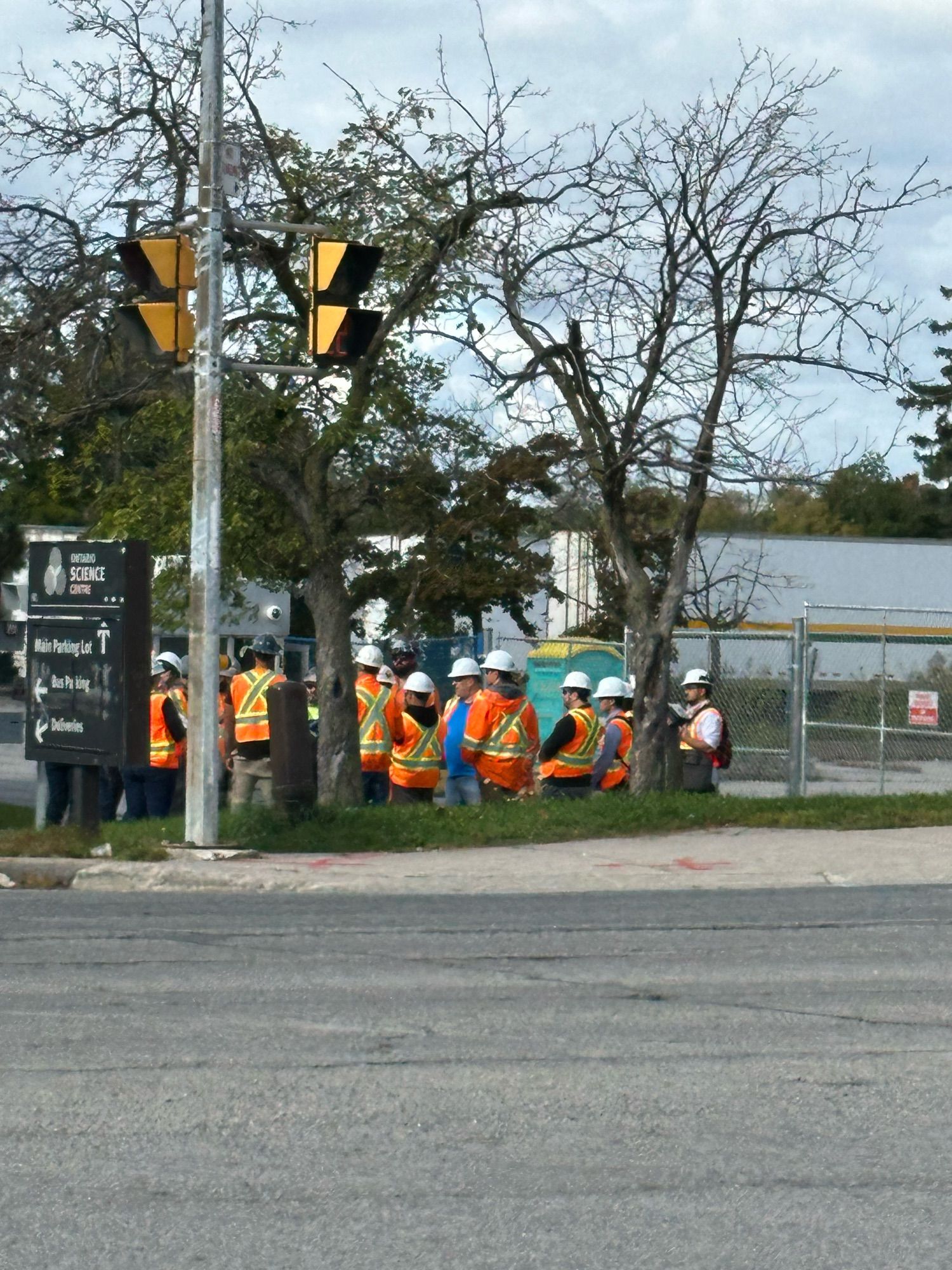 A bunch of people in safety gear and hard hats in front of the Science centre, closeup