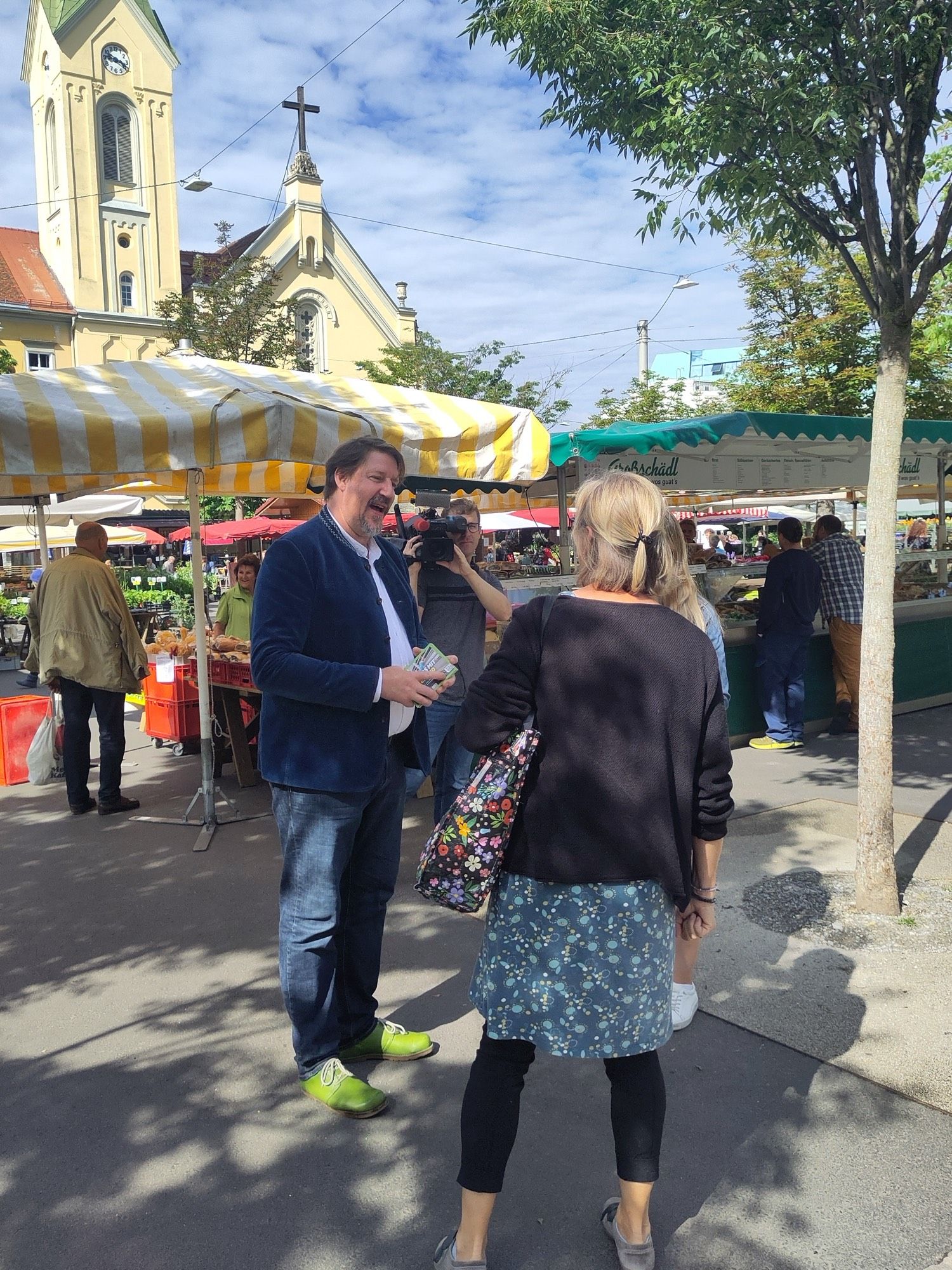 Thomas unterhält sich mit Passantin am Bauernmarkt beim Flyern.