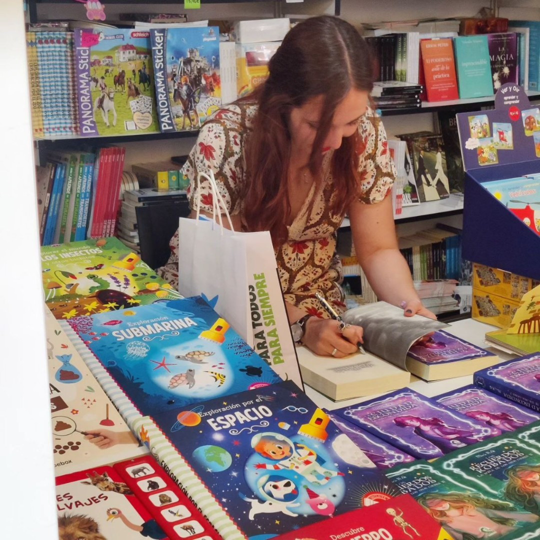 María firmando ejemplares de La ciudad escondida y Los recuerdos robados en la caseta de Interleo.