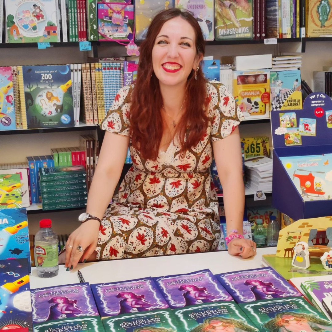 María radiante sonriendo a la cámara con sus dos libros.