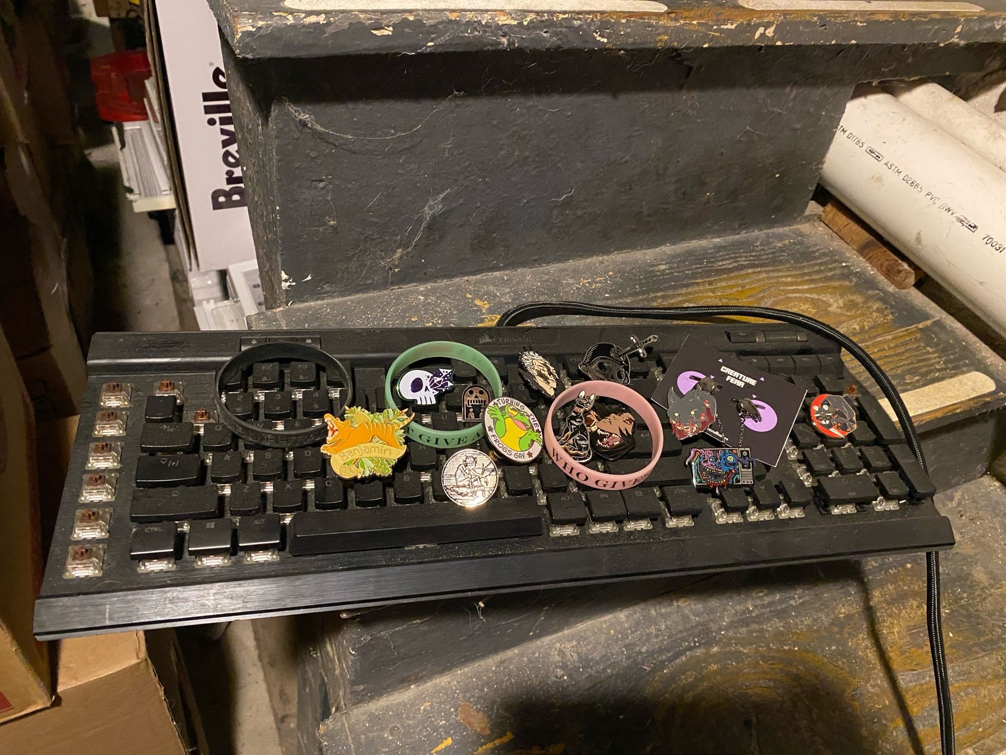 A mechanical keyboard missing Esc, 1, F6, Num-, and some extra function keys on the left. It's coated in ash and dust. 
An array of pins rest atop it.