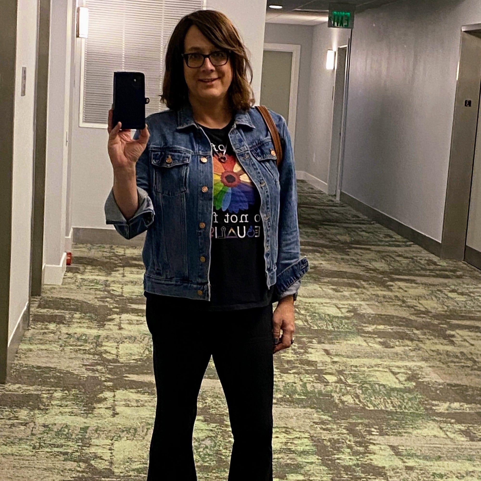 Standing selfie of Lila wearing a jean jacket and yoga pants