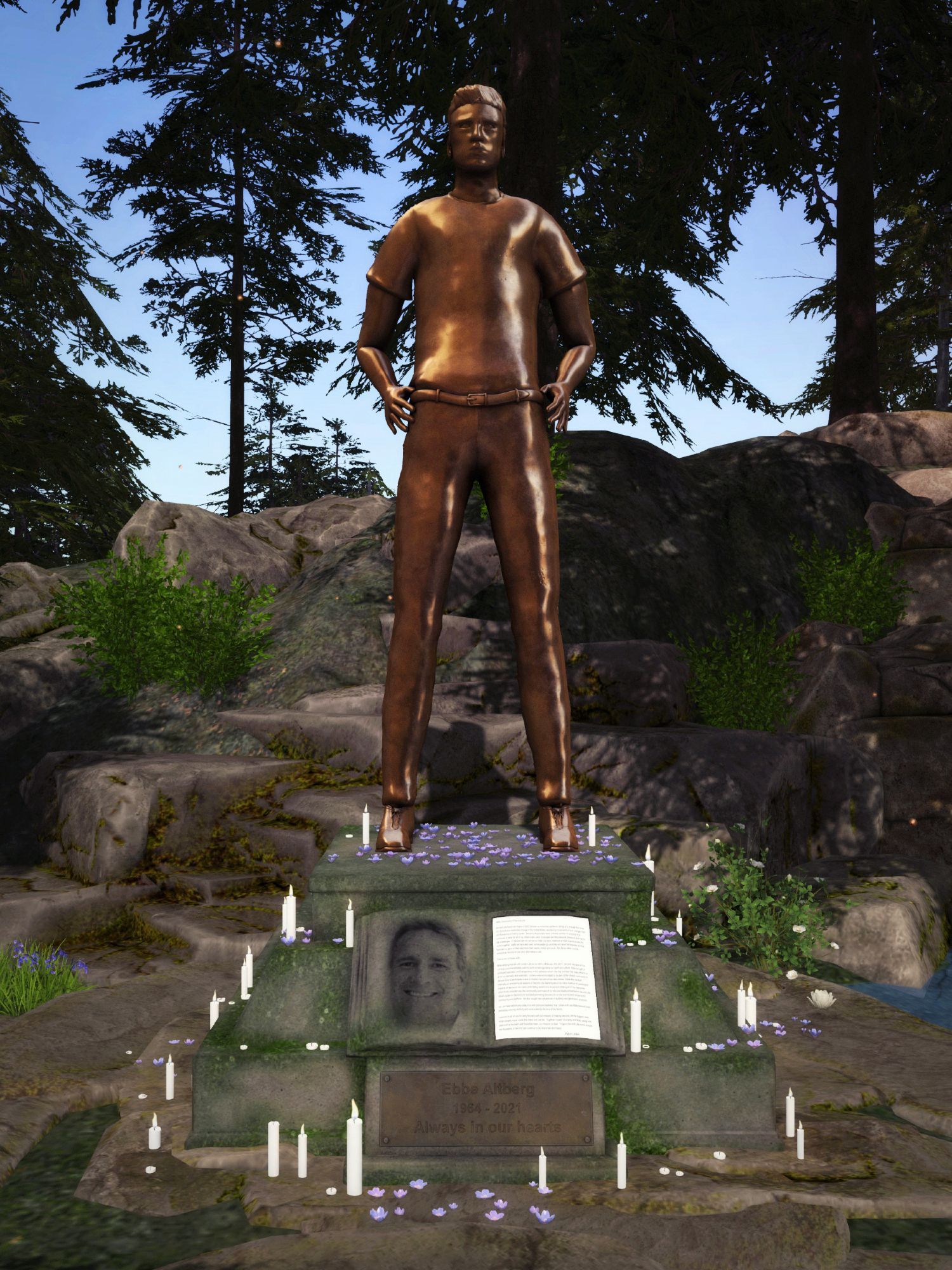 Bronze statue of an Avatar standing proudly on a stone pedestal surrounded by lit candles and purple flower petals, with a forest backdrop. Memorial plaque reads 'Ebbe Altberg 1964 - 2021, Always in our hearts', honoring the former CEO of 'Linden Lab' with a serene and natural setting.

'Second Life' Photo by Wurfi