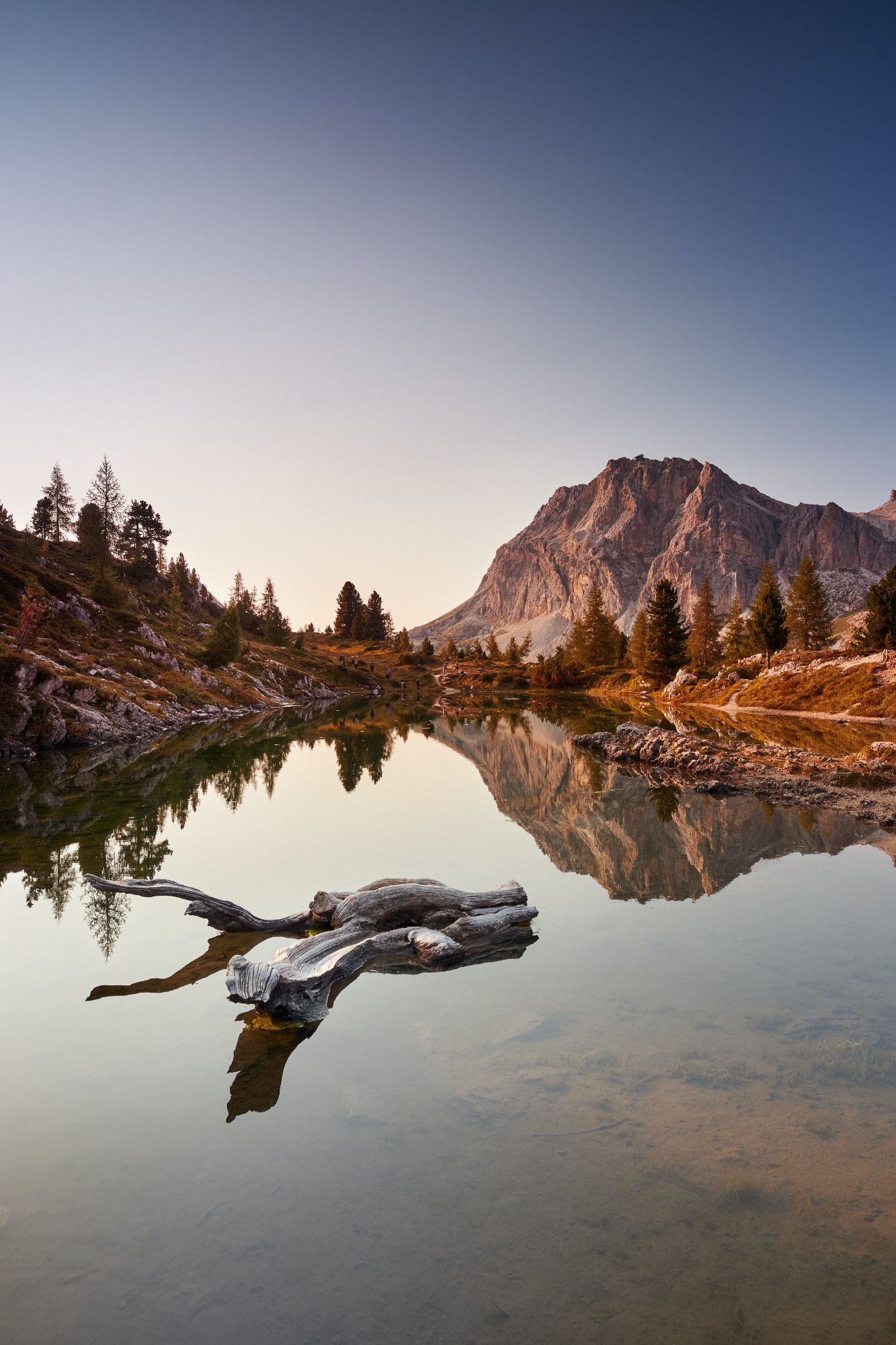 Scenic mountain landscape during sunset with crystal-clear lake reflecting the rocky peak and surrounding pine trees, enhancing the natural beauty and tranquil atmosphere.

Photo by Sara Elison