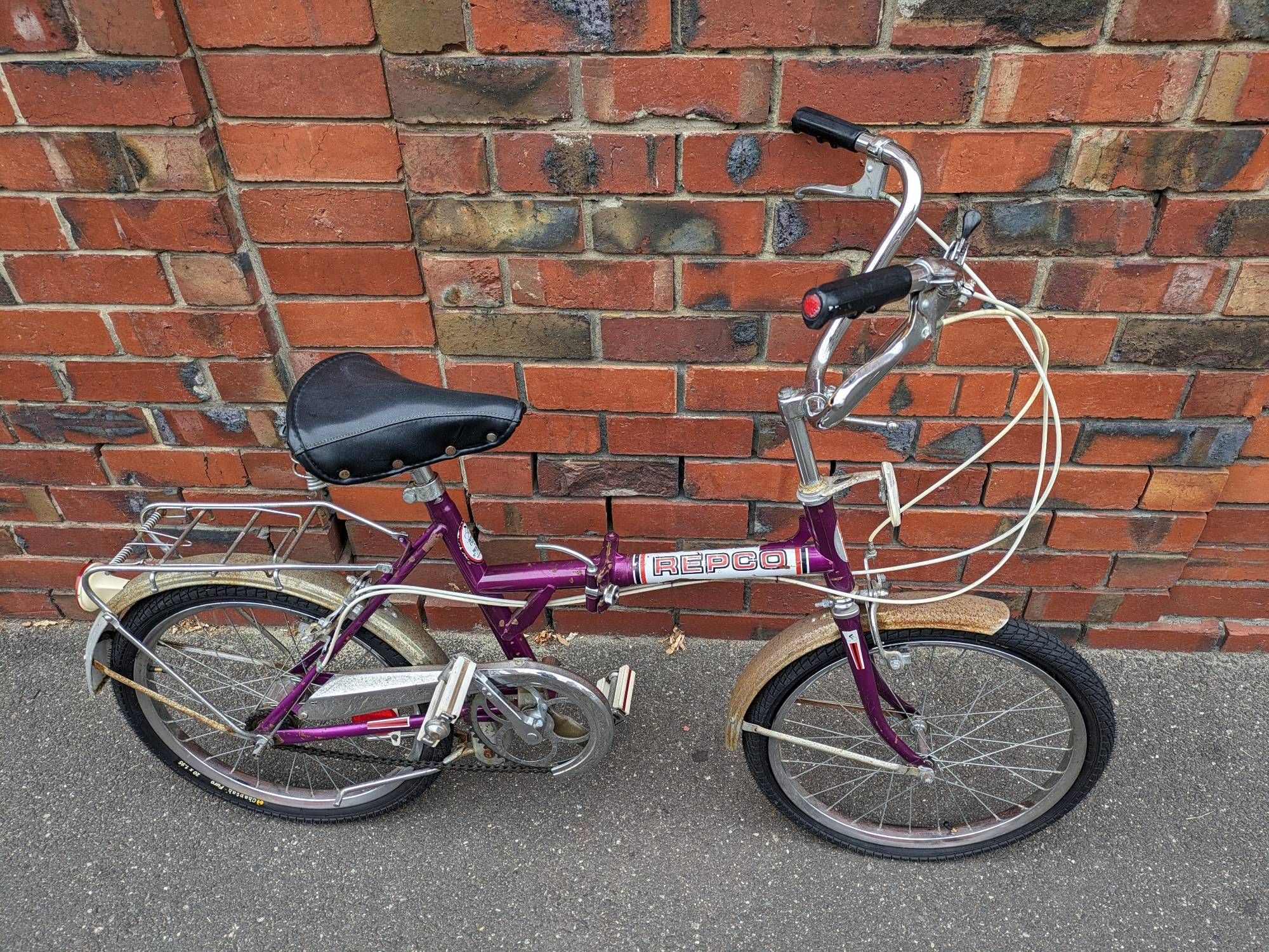 A vintage purple REPCO folding bike. The fenders are rusted and the frame is scratched up, but overall it's in great shape for its apparent age.