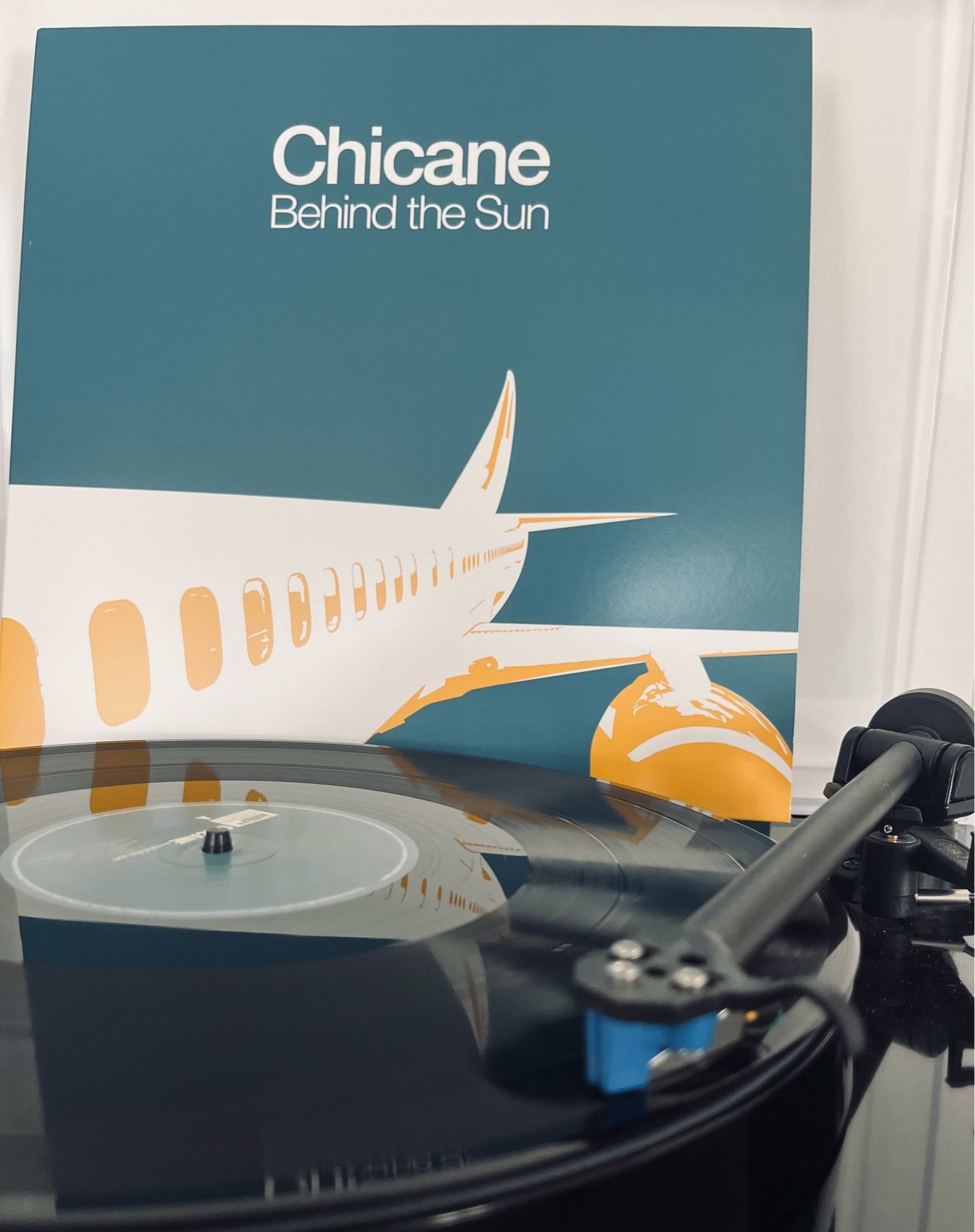 Cover der LP Behind the Sun von Chicane aus dem Jahr 2000. Man sieht die Seite eines Flugzeuge auf blauem Grund. Es ist das zweite Studioalbum von Chicane.