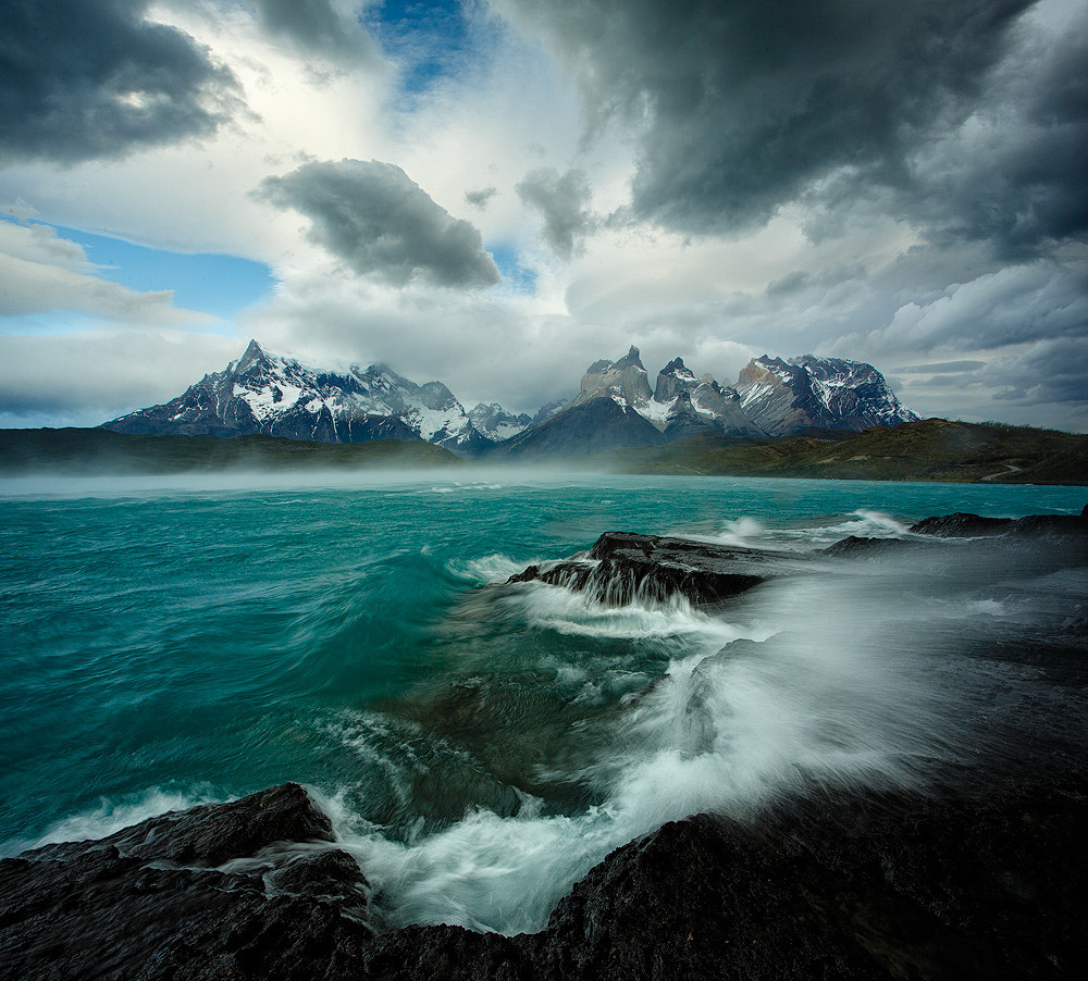 An unforgettable morning in Patagonia's Torres del Paine National Park. Gale force winds transform the calm turquoise waters of Lago Pehoe into a raging sea, blowing away crashing waves and literally lifting the water off the surface!