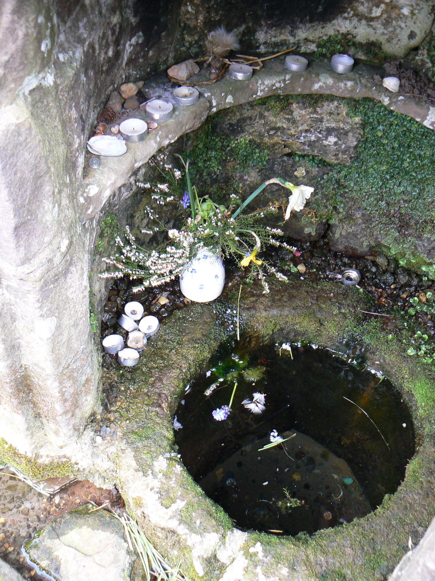 Close up of well opening with flowers, candles