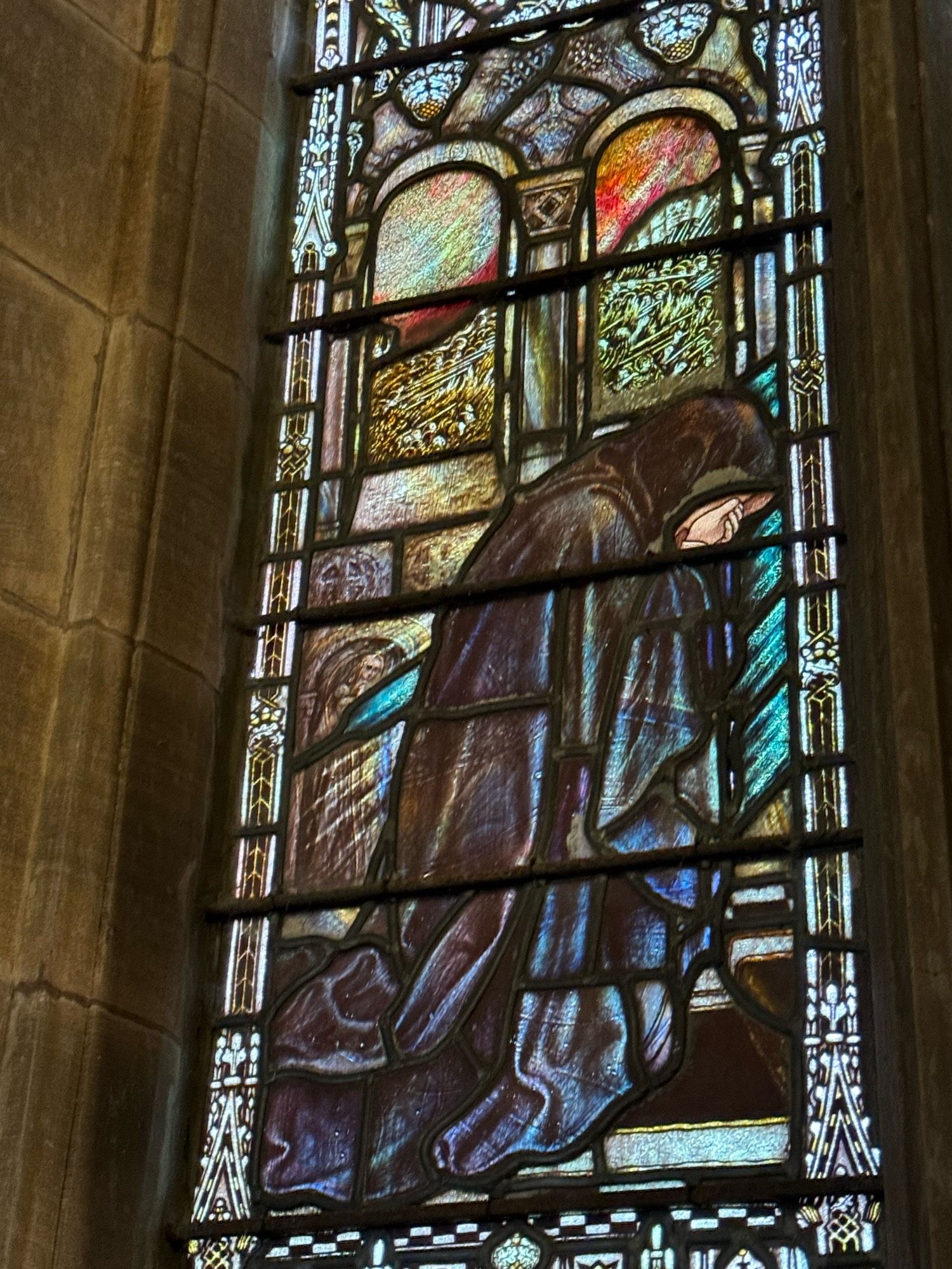 Stained glass with hooded figure grieving