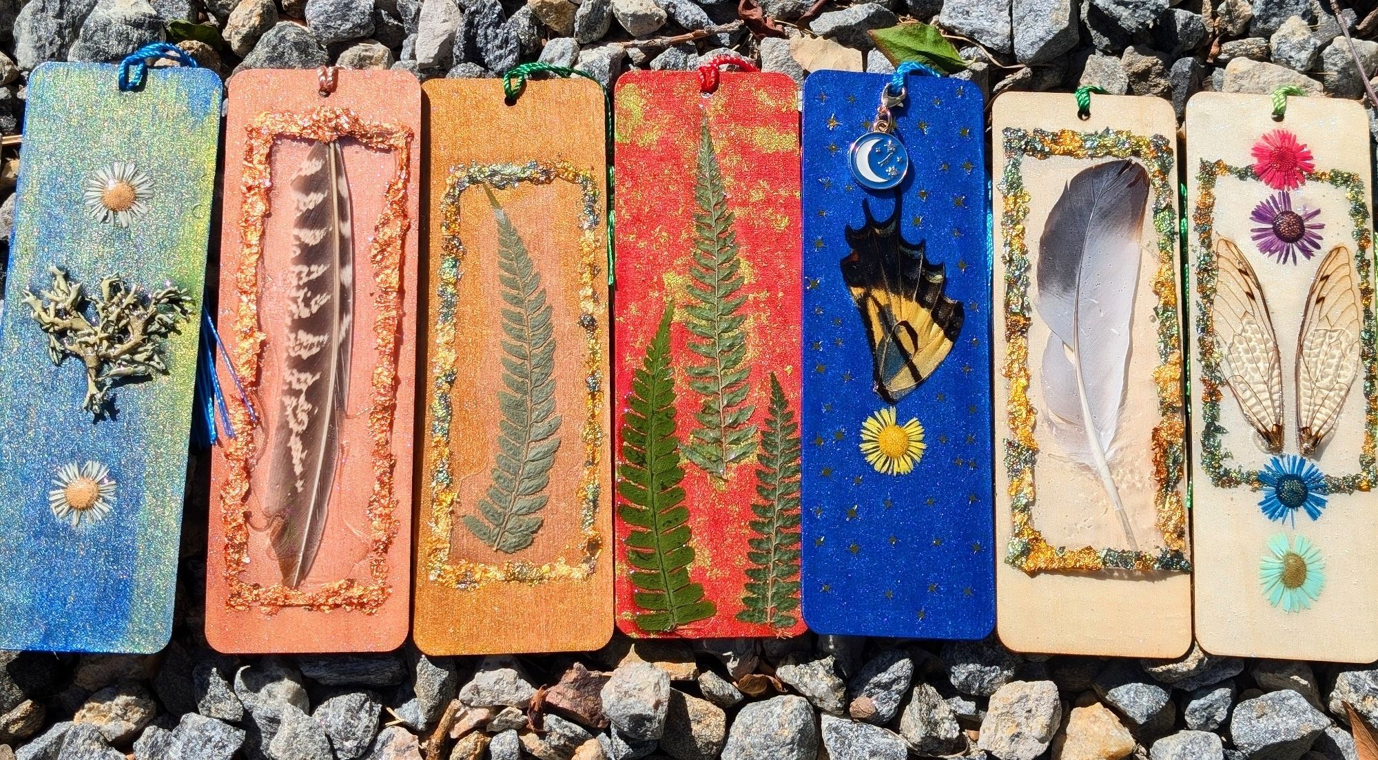 Am array of hand painted bookmarks that feature insect wings, feathers, and pressed botanicals.