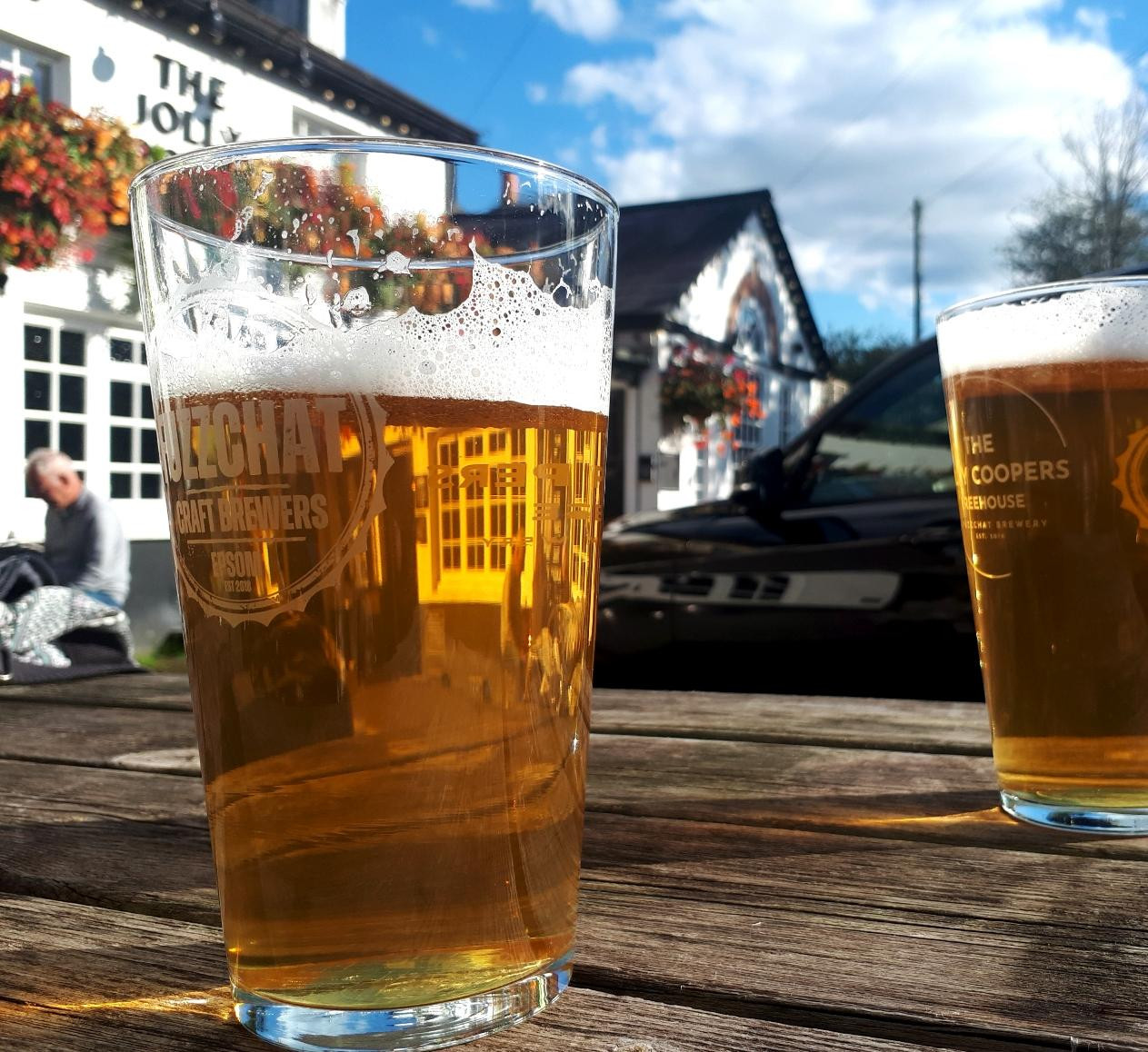 A pint of beer outside a pretty Victorian pub, the hanging baskets still bursting with colour. 