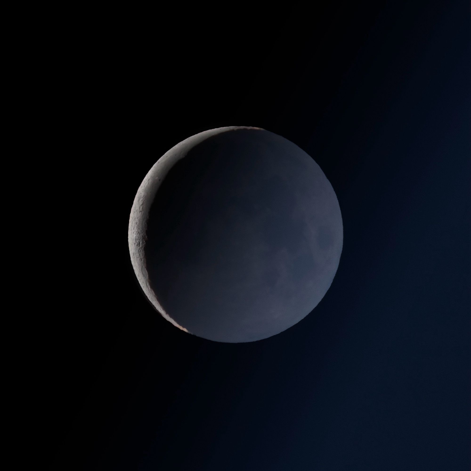 nearly-new moon with very thin detailed crescent and earthshine