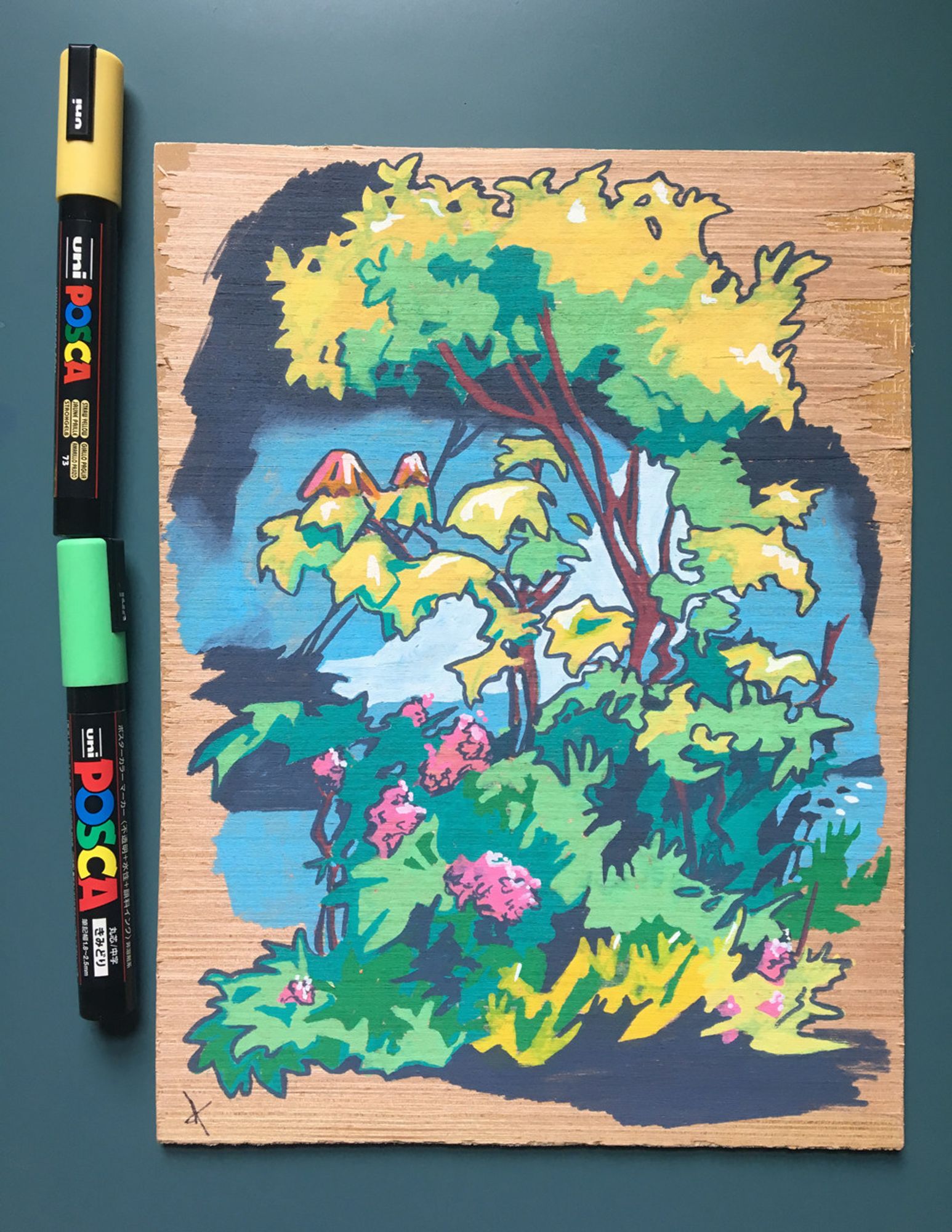 Paint pen drawing on wood of a bundle of bushes with vibrant, pink flowers. The sky is blue behind the plants. The leaves are various shades of green and yellow. The grain of the wood is shown bordering the edge of the painting.