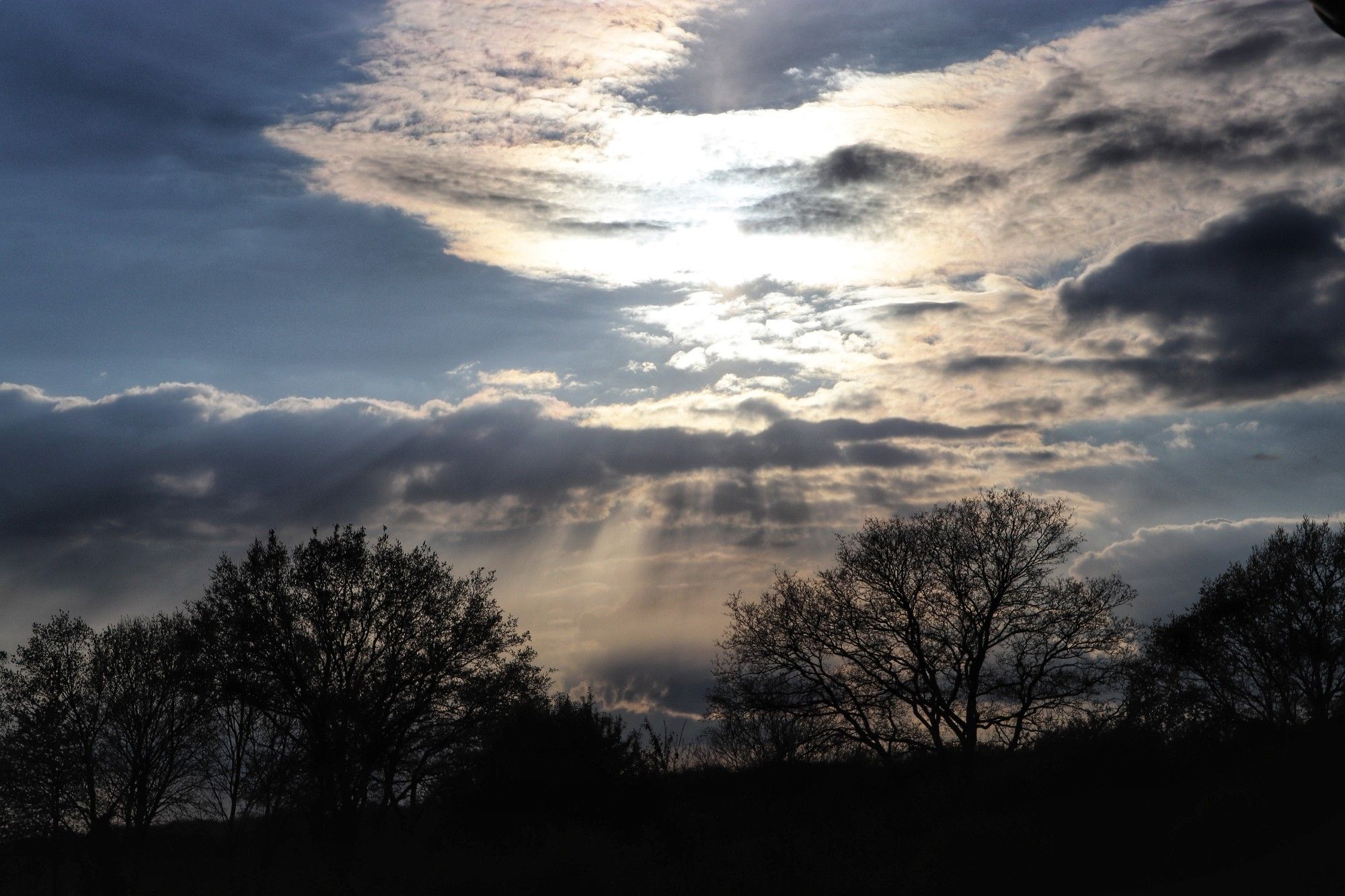 Die Sonne hinter Wolken am Abendhimmel