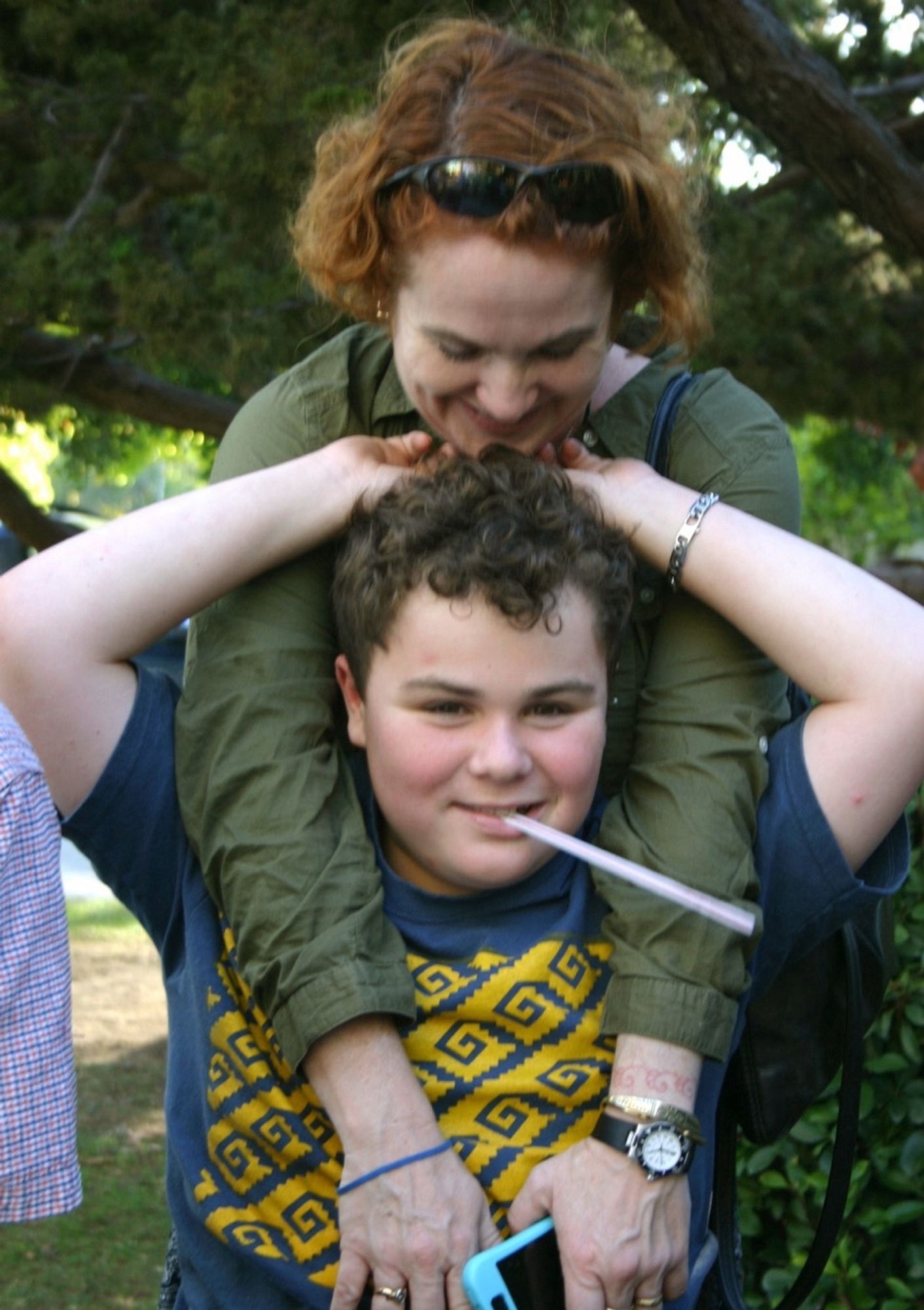 Photo Steve took of me and Leo about 10 years ago. Leo is smiling widely with a straw in his mouth, and reaching up to my face. I have my arms over his shoulders and my chin on his head and am looking down at him lovingly.