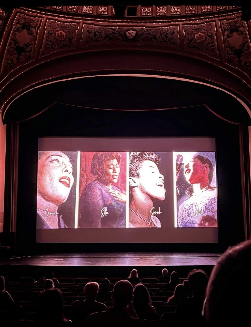 A large theatre stage showing a picture of Carmen McRae, Sarah Vaughan, Ella Fitzgerald & Billie Holliday.