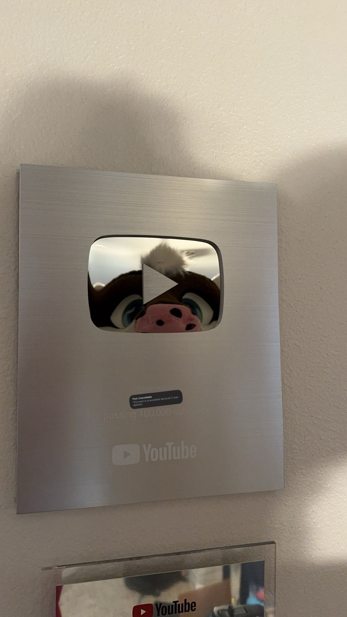 Cobalt fursuit peaking in the reflection of a silver creator award from YouTube