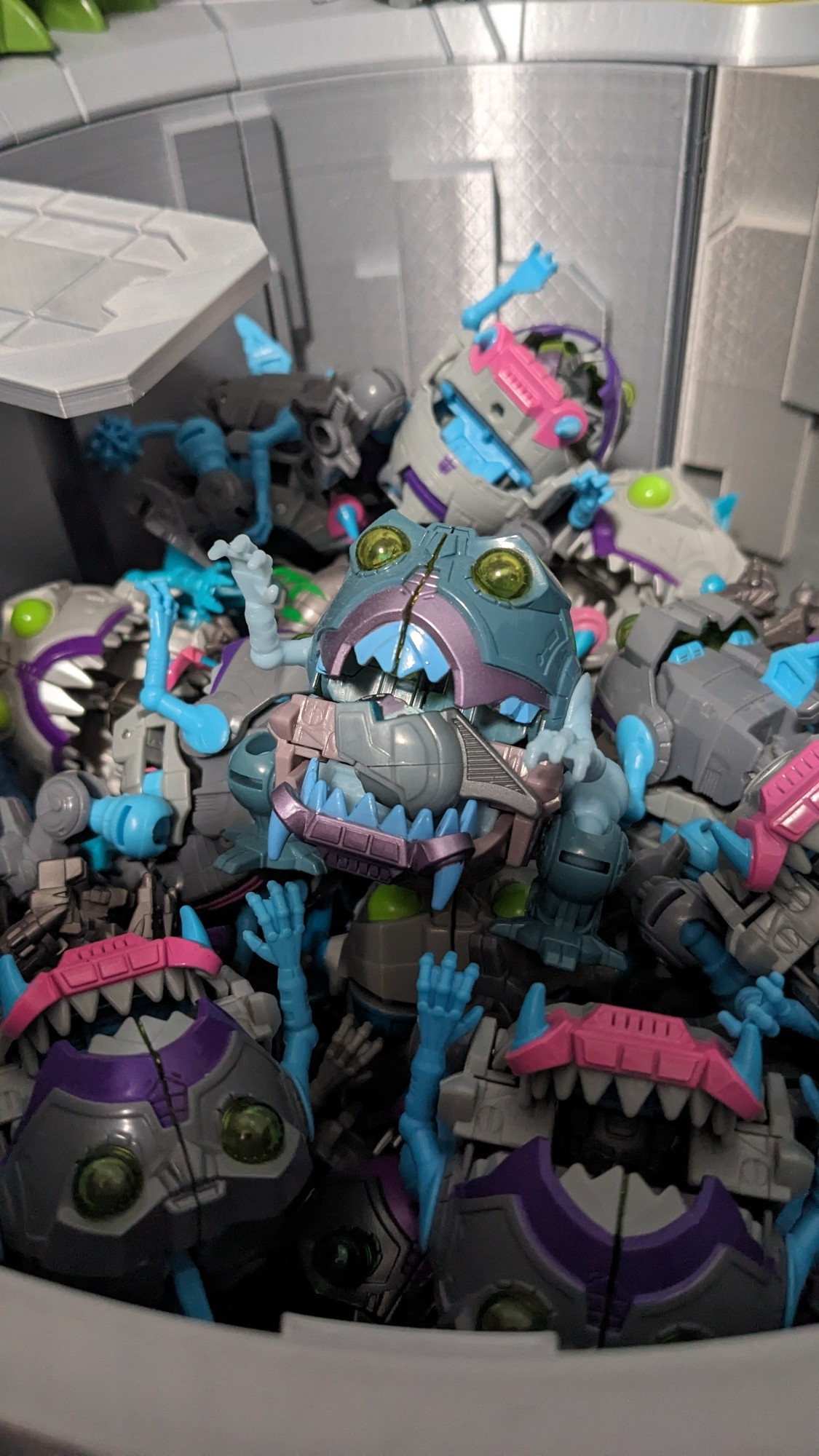 A group of sharkticons in a pit with one holding an allicon head in its jaws