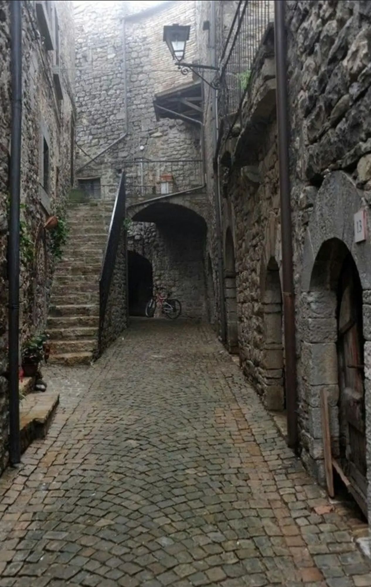 An alleyway with a bunch of curved archways on the right side. At the back of the alleyway is a short staircase leading to a balcony.

It's essentially the live action version of the Capra Demon boss fight from Dark Souls