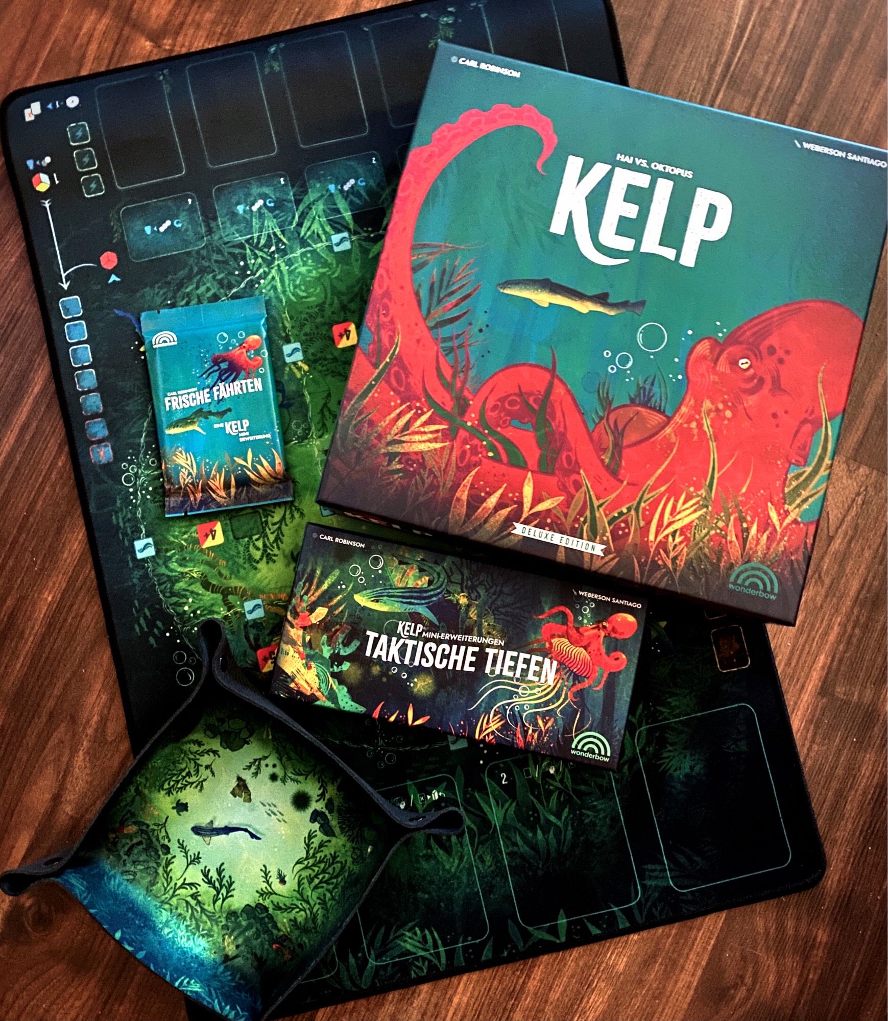 Ein Dicetray und eine Spielmatte mit Unterwasserszenen bedruckt das Brettspiel Kelp, die Erweiterung Taktische Tiefen und Frische Fährten.