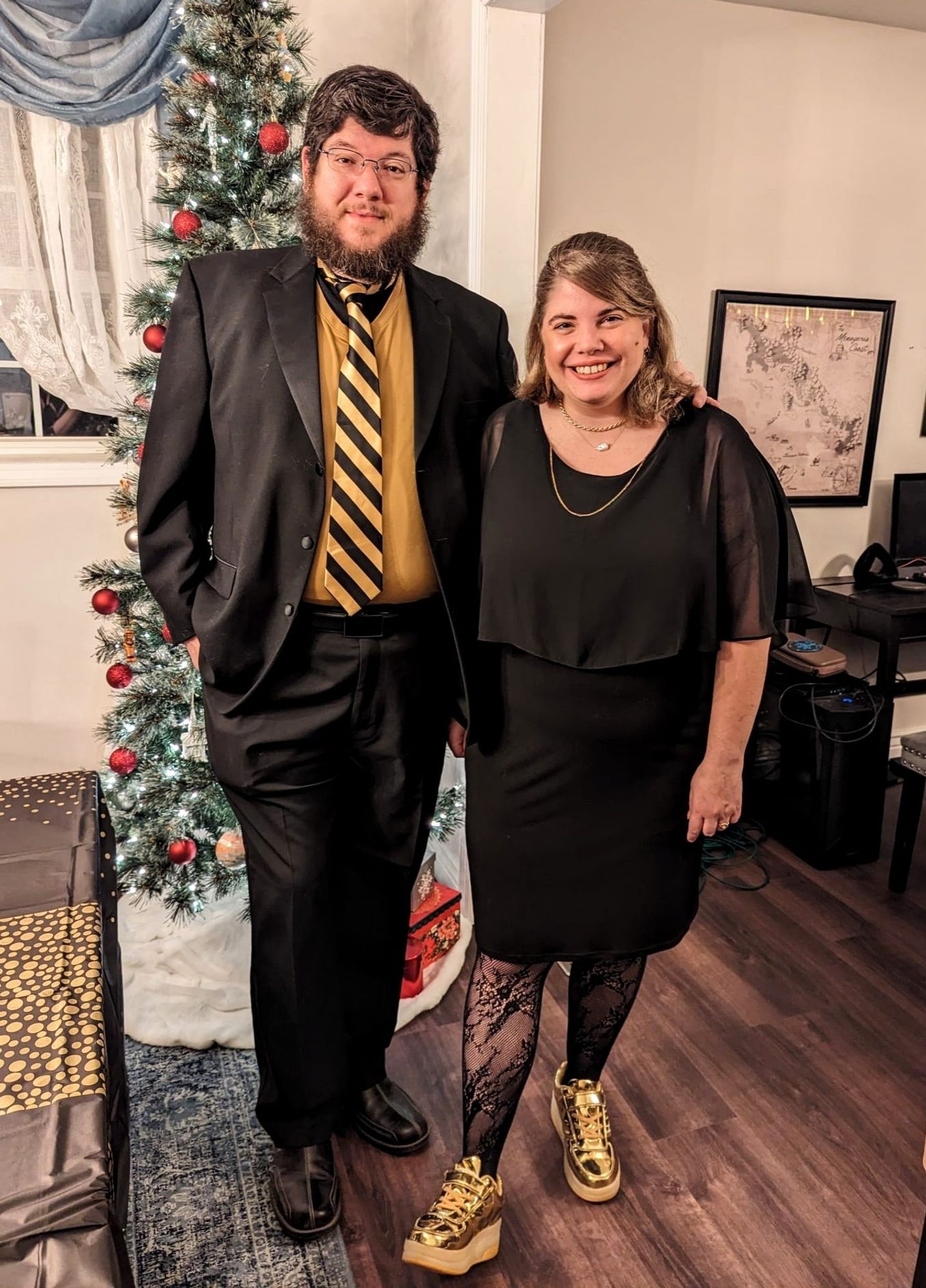 A tall man and shorter woman wearing fancy black and gold outfits.