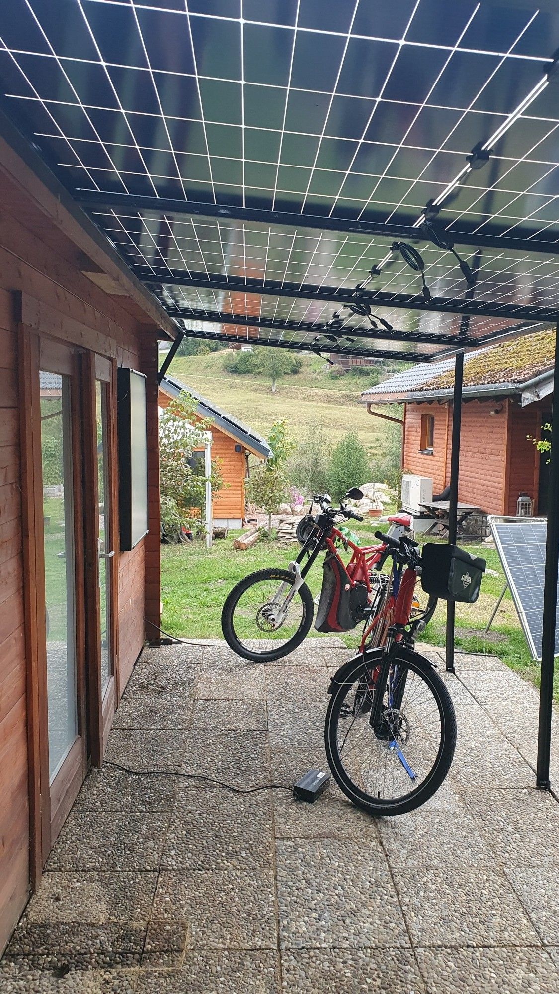 Unterm Vordach stehen eBikes vor der Holzhütte.