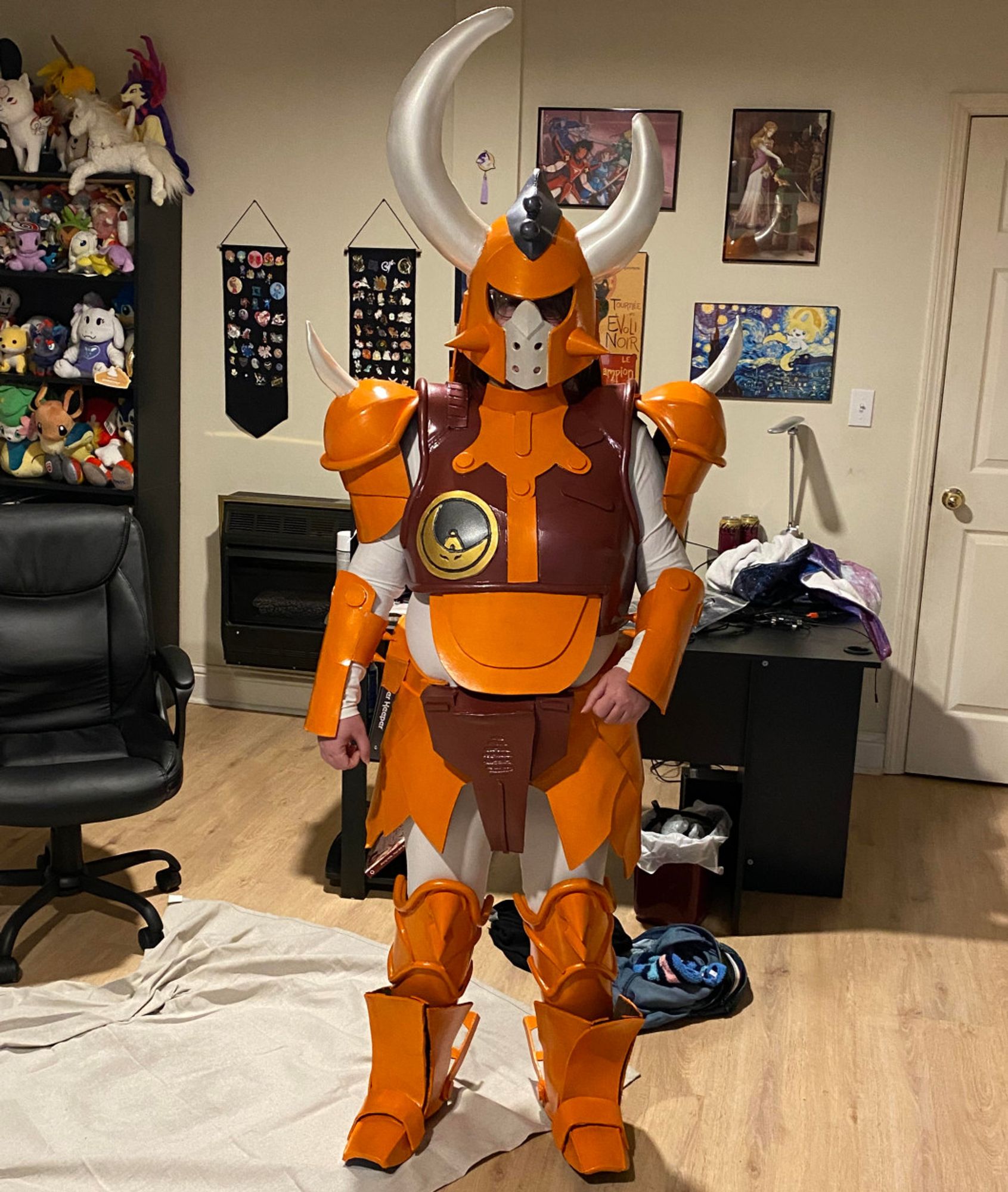 A suit of orange, maroon, and silver painted EVA foam with a black and gold emblem. The helmet has asymmetrical horns and the shoulders have curving spikes.