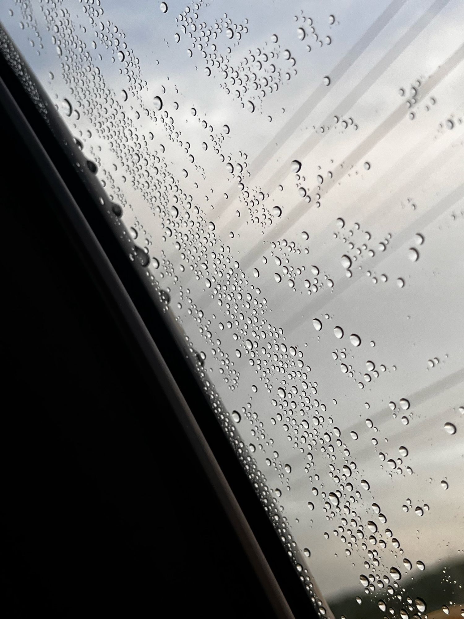 Photo of water drops on a window with a cloudy grey sky