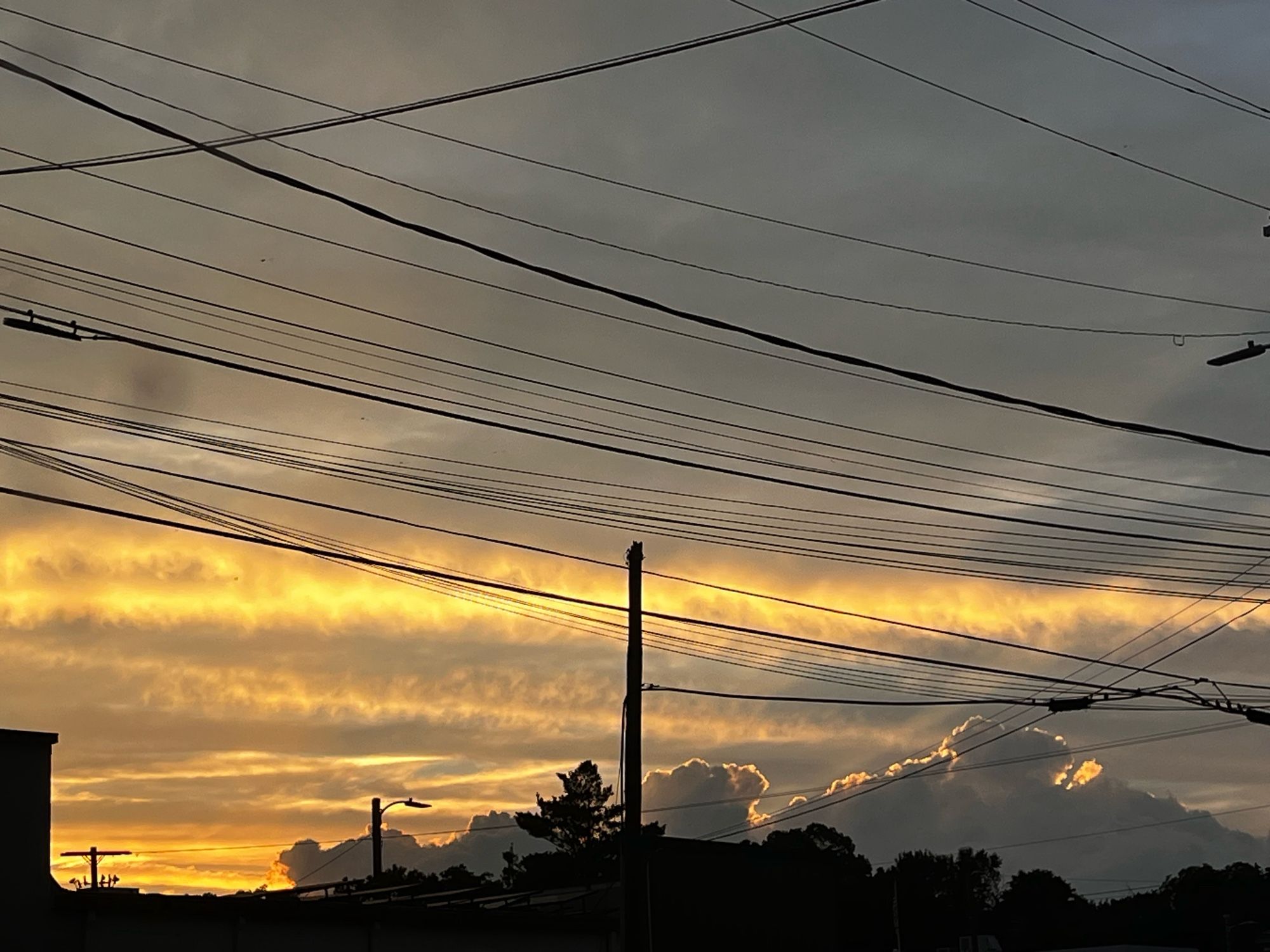 Photo of a yellow and grey sunset behind powerlines