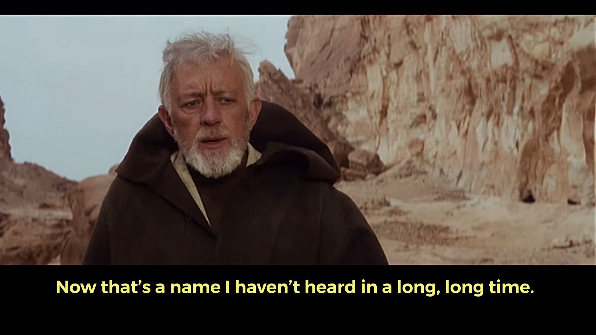 Obi Wan Kenobi in A New Hope - an older man with white hair and beard in a brown hooded cloak looking puzzled  “now that’s a name I haven’t heard in a long long time”