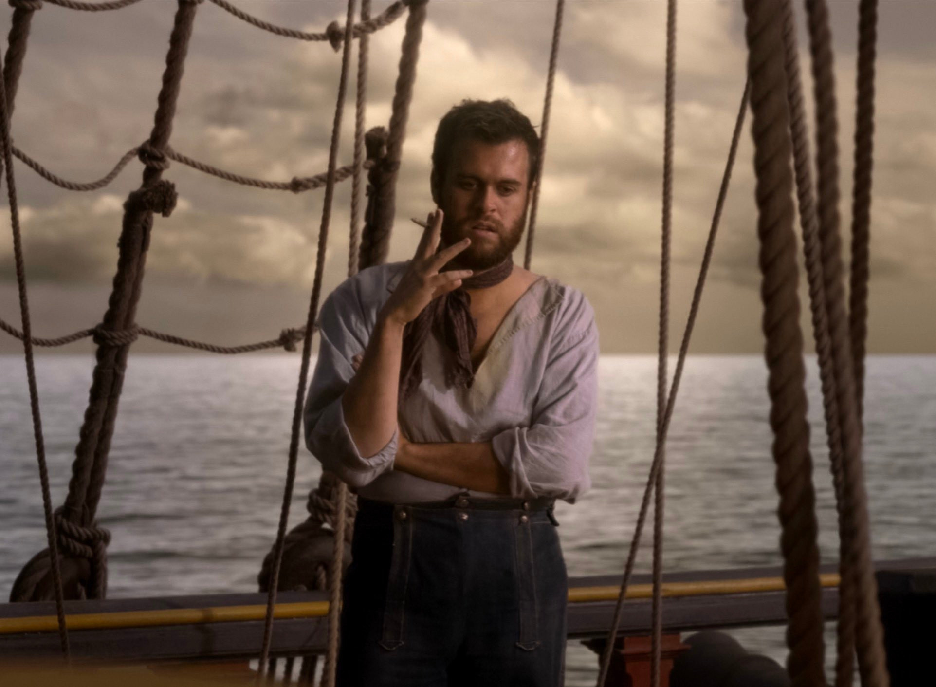 Lucius is standing on deck smoking a cigarette. 