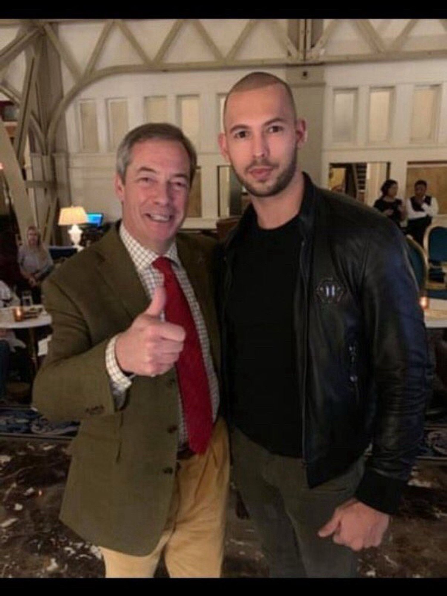 Picture of Nigel Farage giving the thumbs up sign, while standing shoulder to shoulder with alleged rapist and human trafficker Andrew Tate, now being investigated for trafficking and sex with minors.