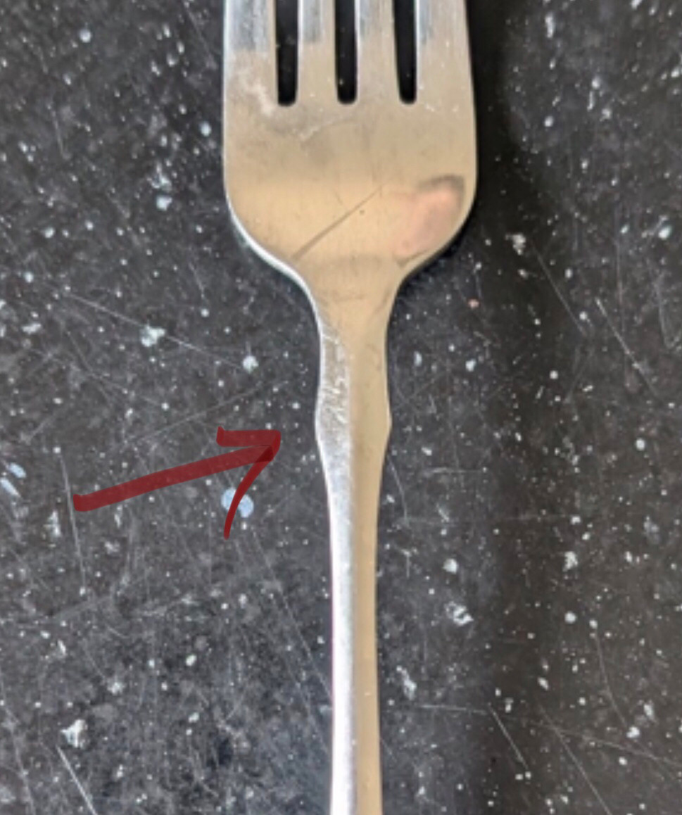 A close up of the above fork, with a red arrow indicating the most offensive part just below the tines.
