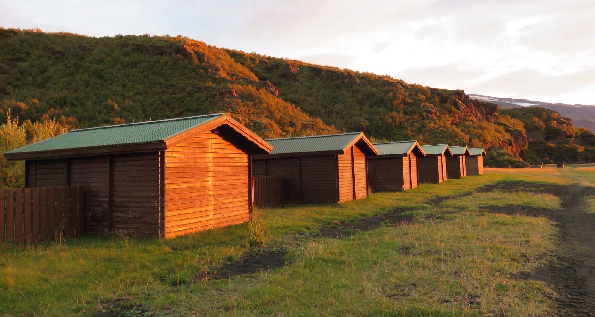 Petits chalets et colline éclairés d'une belle lumière orange au coucher de soleil. Volcano Huts à Þórsmörk, Islande (septembre 2014)