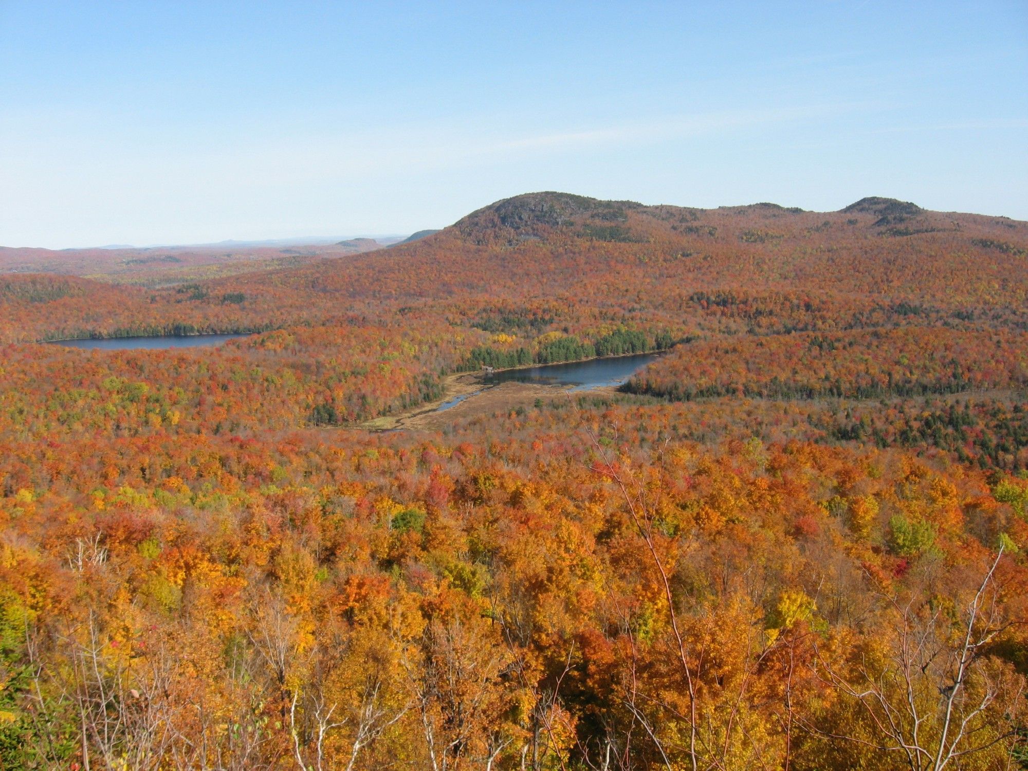 Vue à partir du Pic de l'ours. On voit deux plans d'eau, une montagne. Les arbres sont de couleur orangé. Parc national du Mont-Orford (octobre 2008)