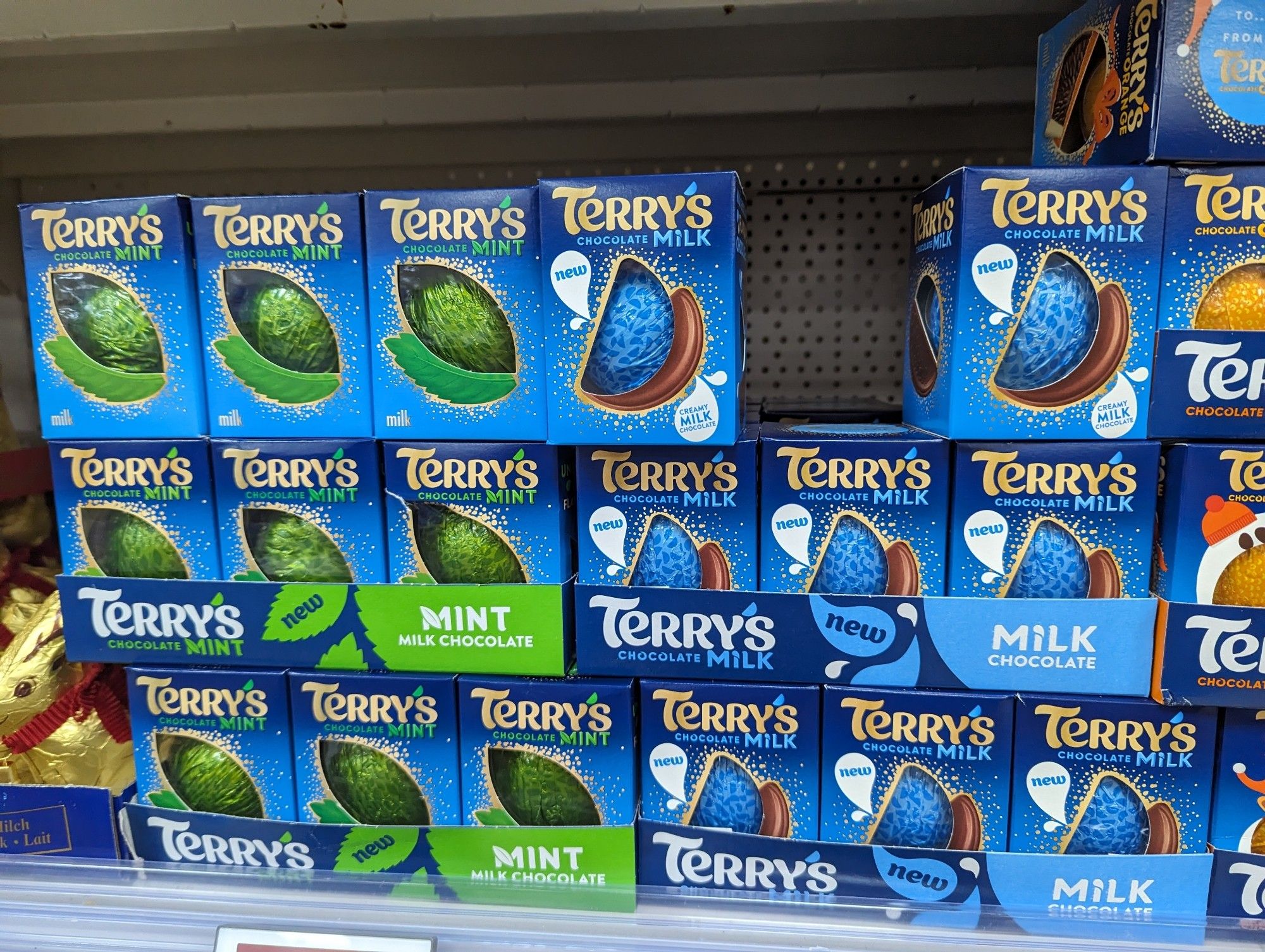 A photo of a supermarket shelf with three different flavours of Terry's chocolate "orange" - orange, mint, and new, regular milk chocolate.