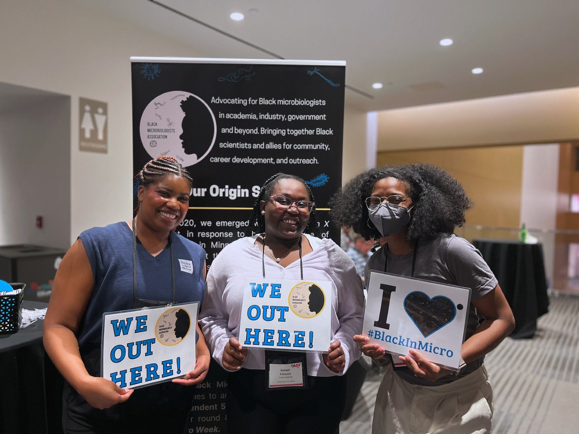 Conference attendees holding signs that say "We Out Here" and "I love #BlackInMicro"