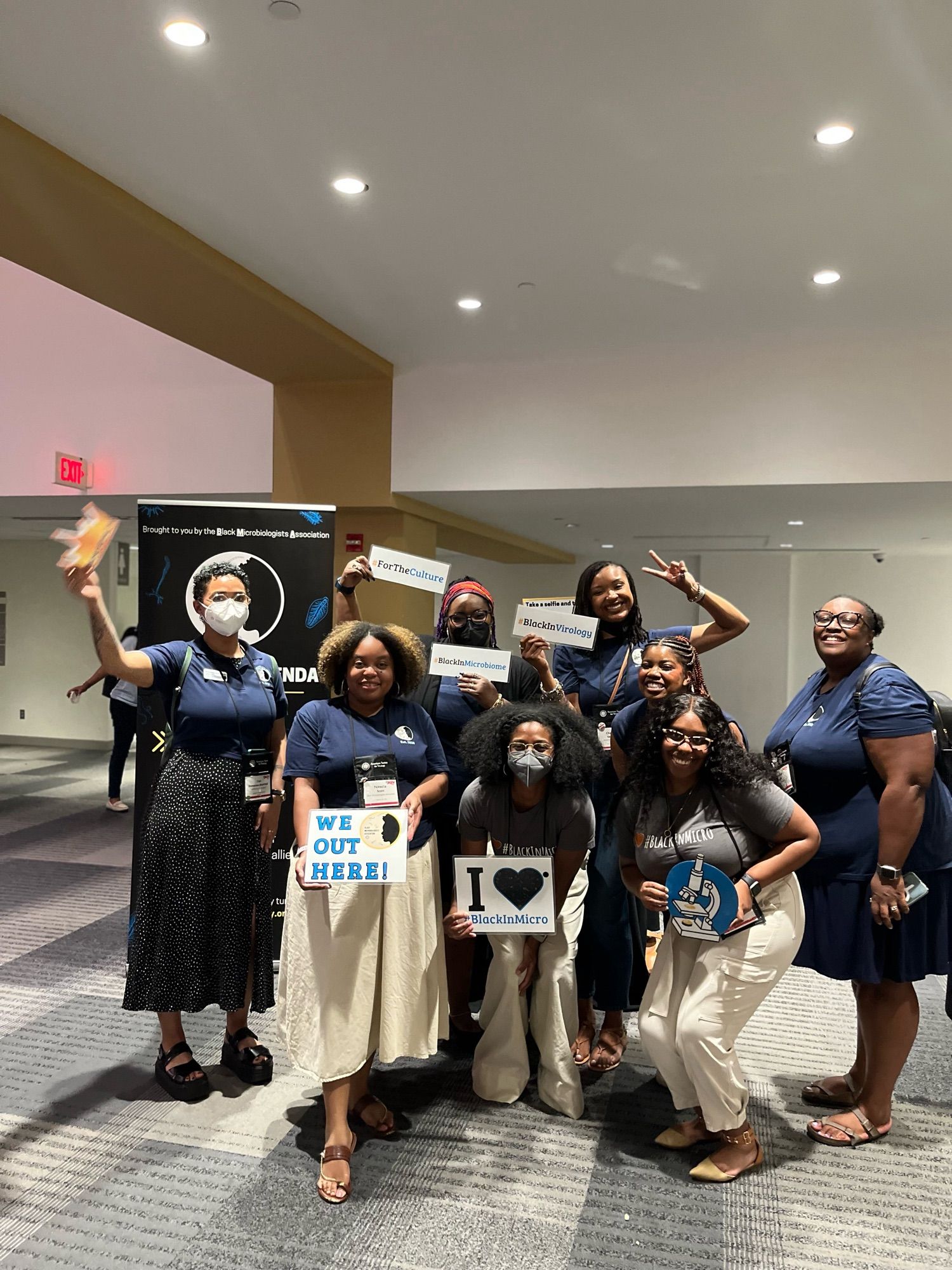 Group of 8 BMA organizers holding selfie signs during the Evening Social at ASV 2024