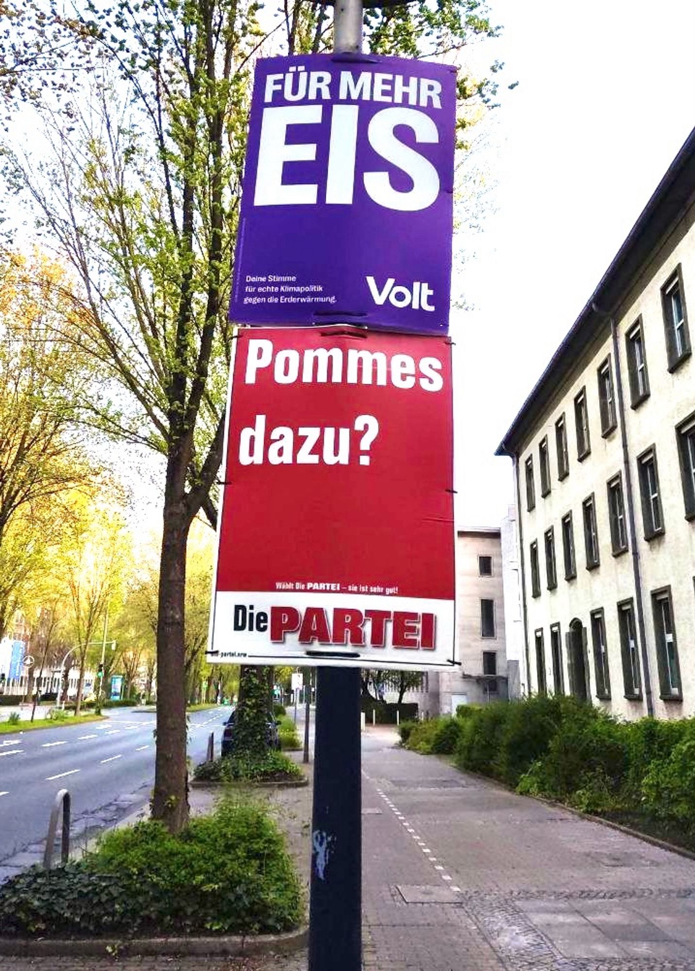 Ein lila Plakat mit der Aufschrift „Für mehr Eis“. Darunter ein Plakat von Die PARTEI mit der Aufschrift „Pommes dazu?“