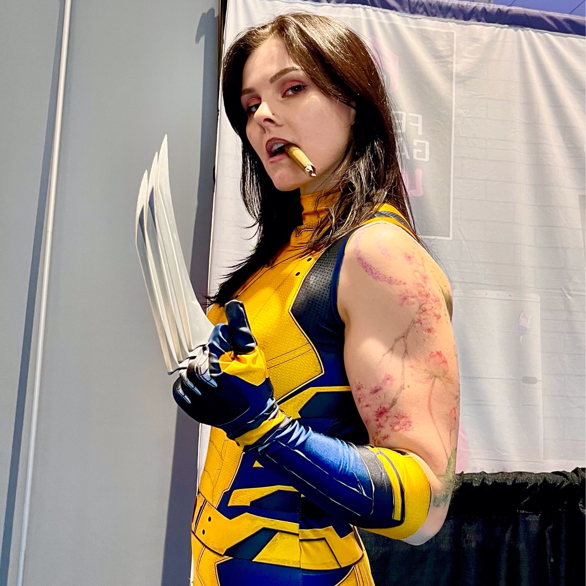 A white woman dressed as Wolverine with her claws extended and chomping on a cigar