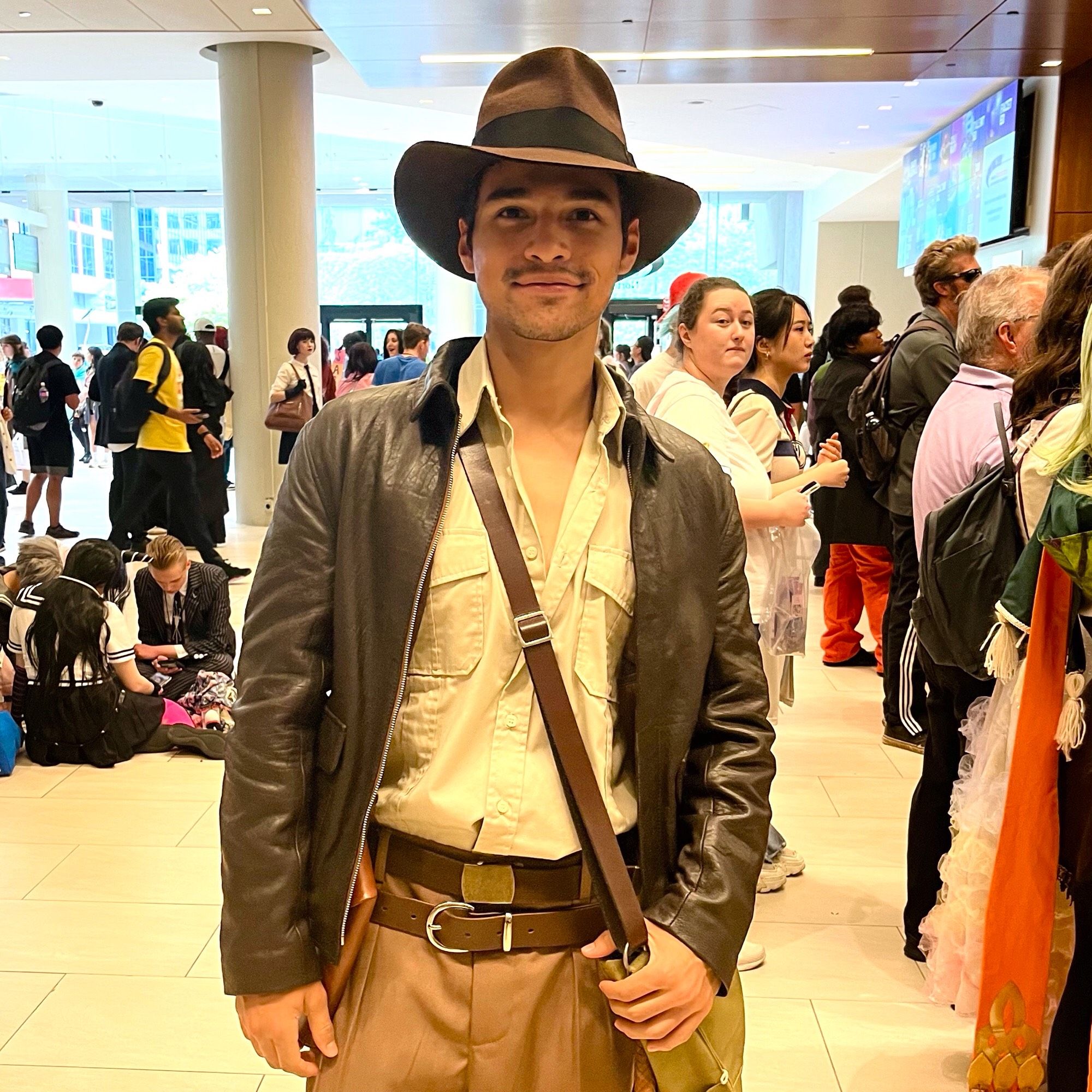 A young Latino guy dressed in Indiana Jones’s brown leather jacket and fedora